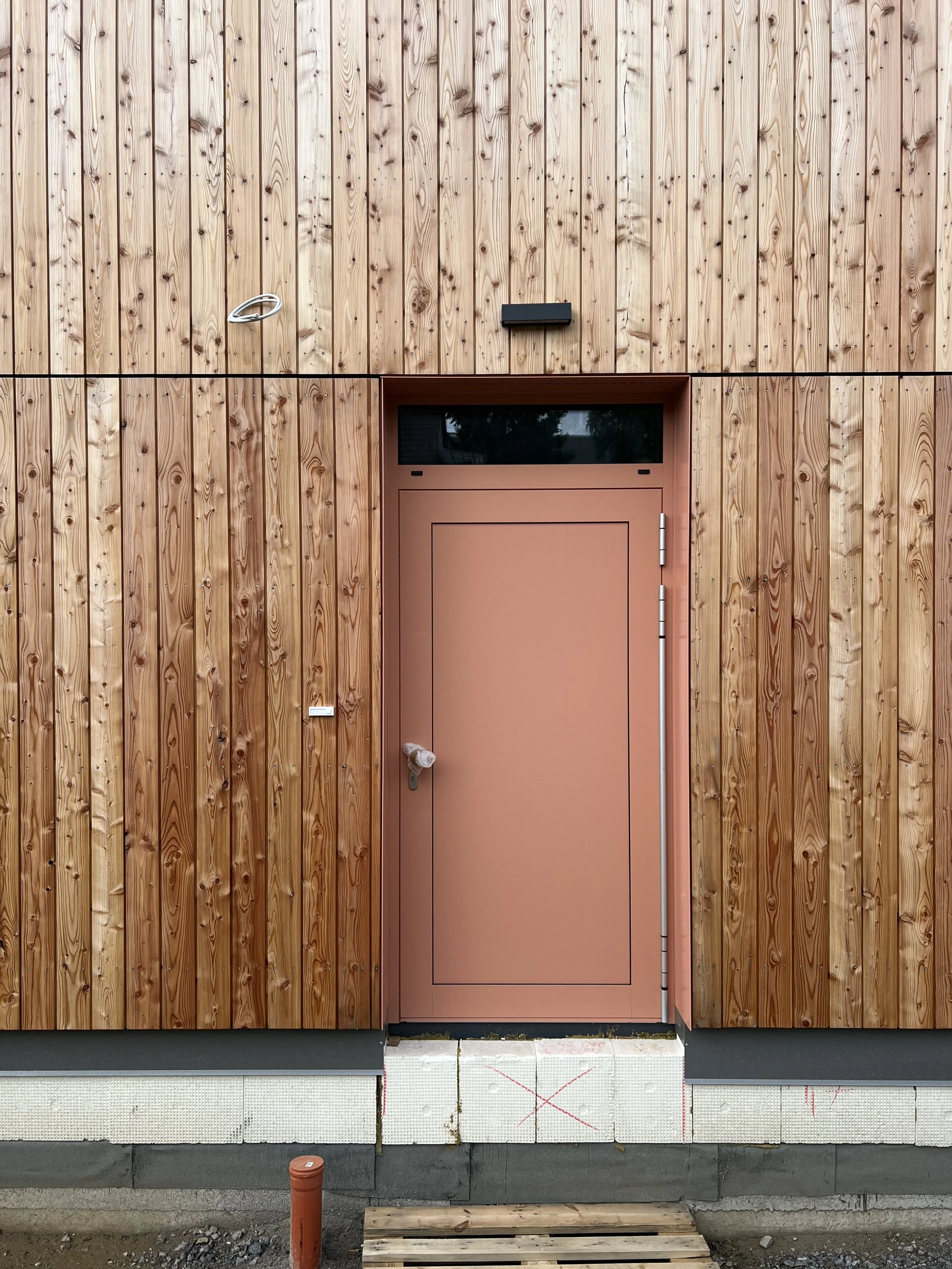 Ein Gebäude mit einer Holzfassade und einer pinkfarbenen Tür.