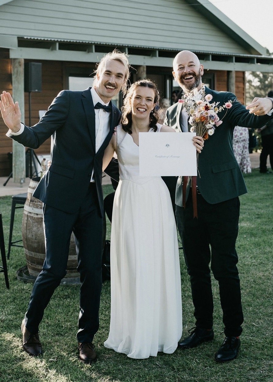 A happy couple married by friends standing next to wedding decoreations