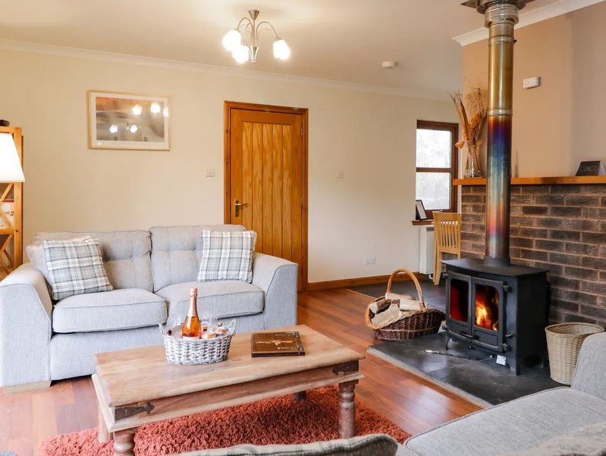 Fersit Log Cottage living room with cosy sofas and log fire in the Scottish Highlands.