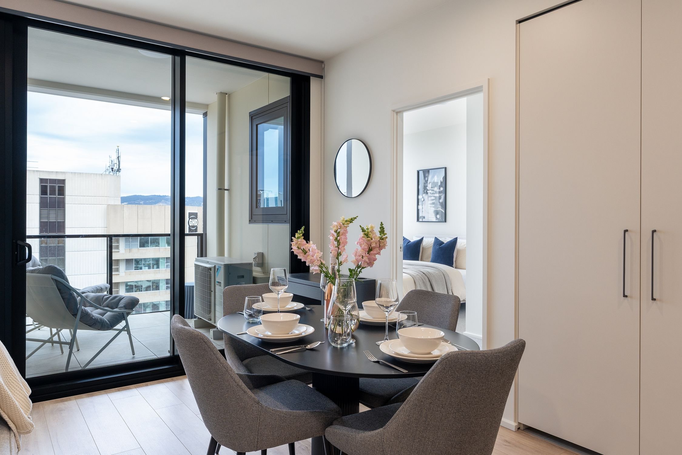 dining room area in apartment in Adelaide, Airbnb short stay. Overlooking Victoria Square with balcony and bedroom behind the dining area