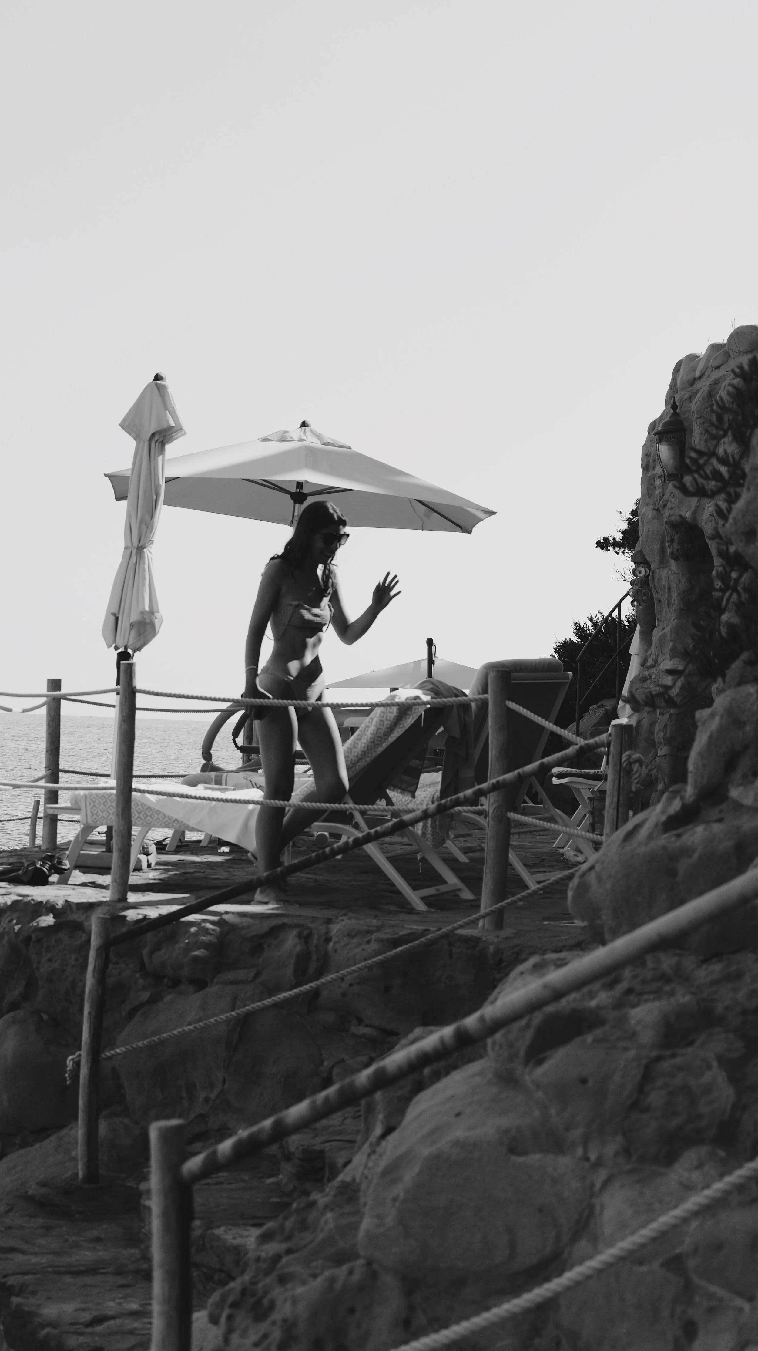 Woman under umbrella waving with glases