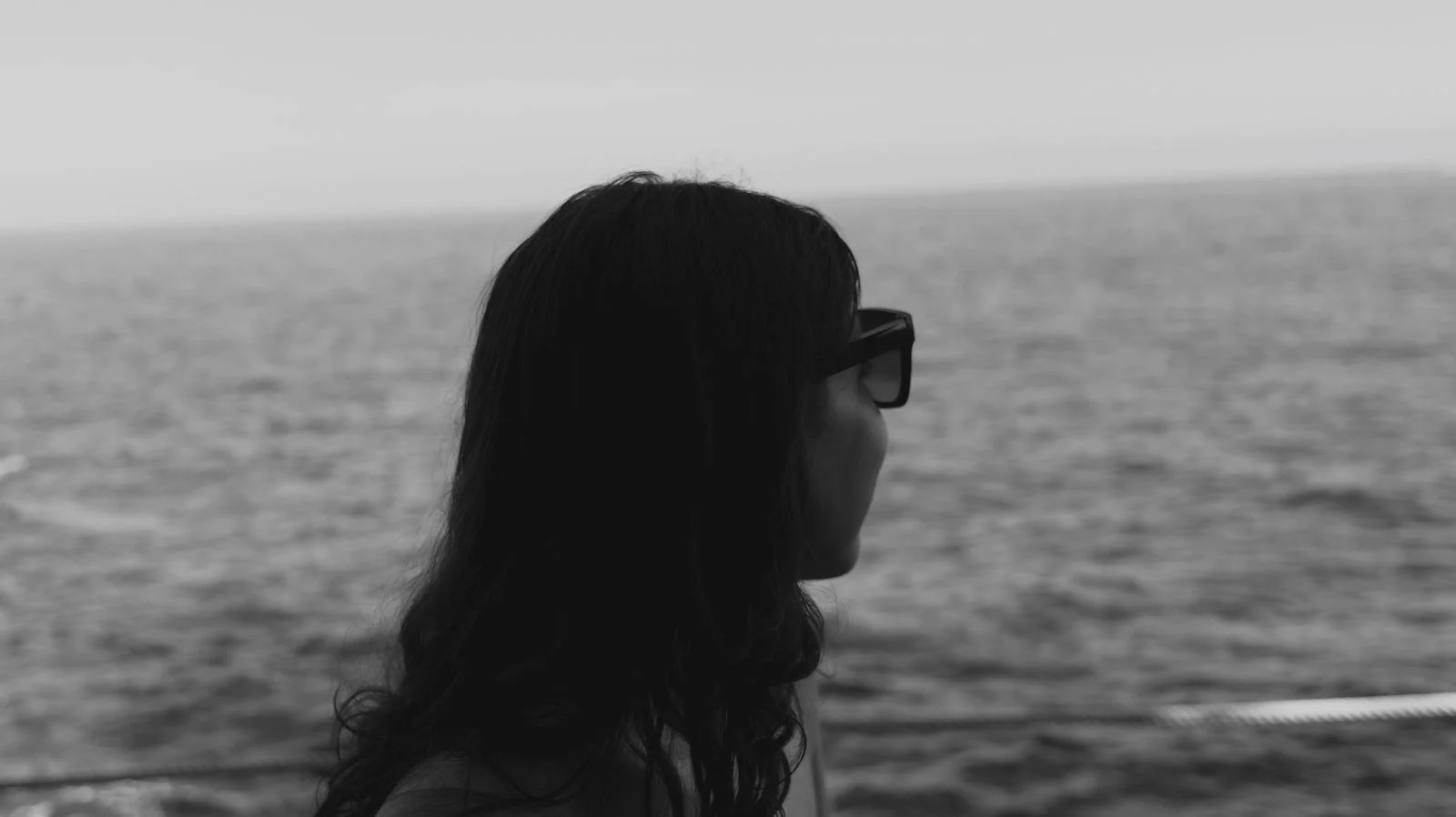 woman looking back over the sea with sunglases