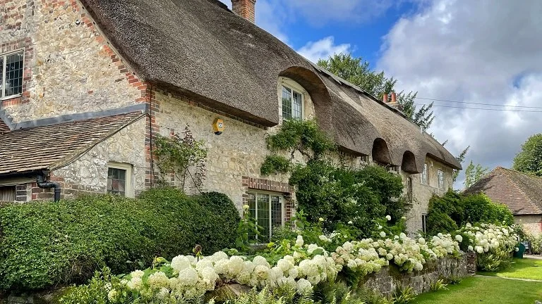 Thatched roof cottages and overflowing flowerbeds in Amberley UK