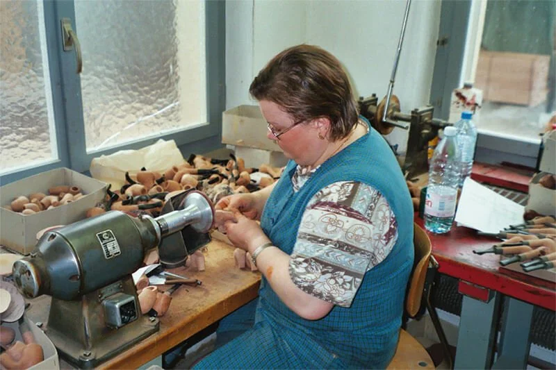 Frau arbeitet an einer Werkbank in einer Werkstatt, um Armreifen herzustellen, mit verschiedenen Werkzeugen und Materialien