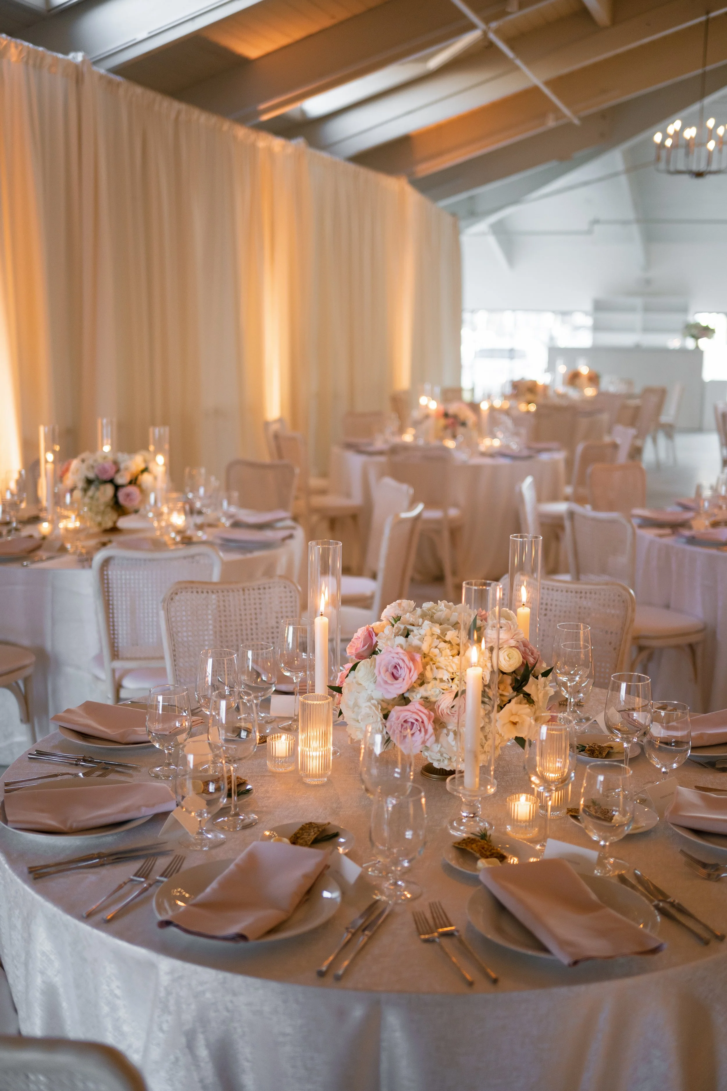 A close up of a wedding reception table, with soft candlelight and pink details.