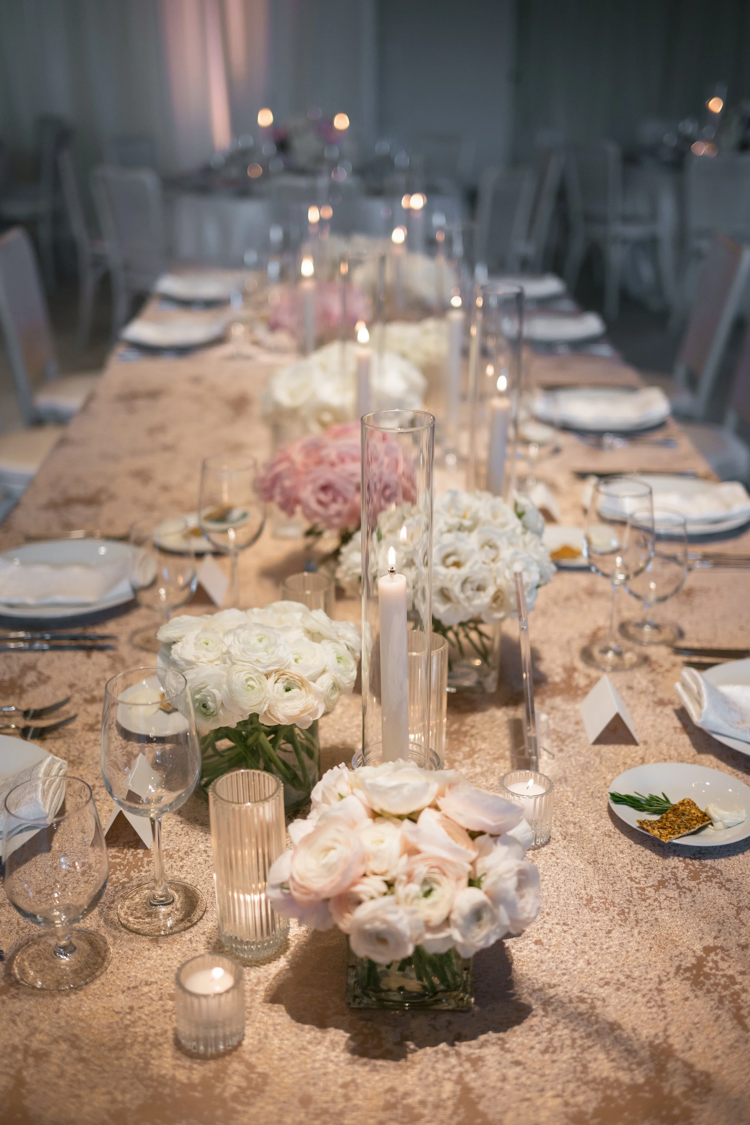 Close-up detail shots from a wedding reception, with rose gold accents in the floral centerpieces and candlelit table settings.