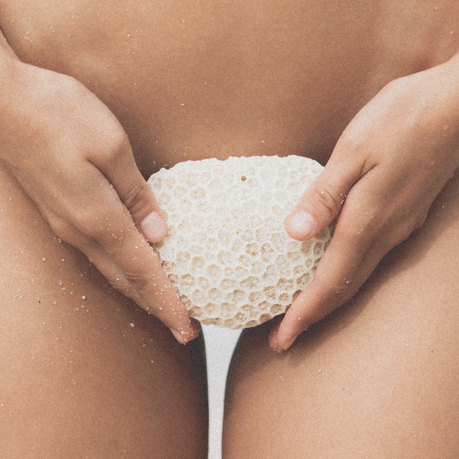 woman holding a piece of white coral in front of her body on the beach