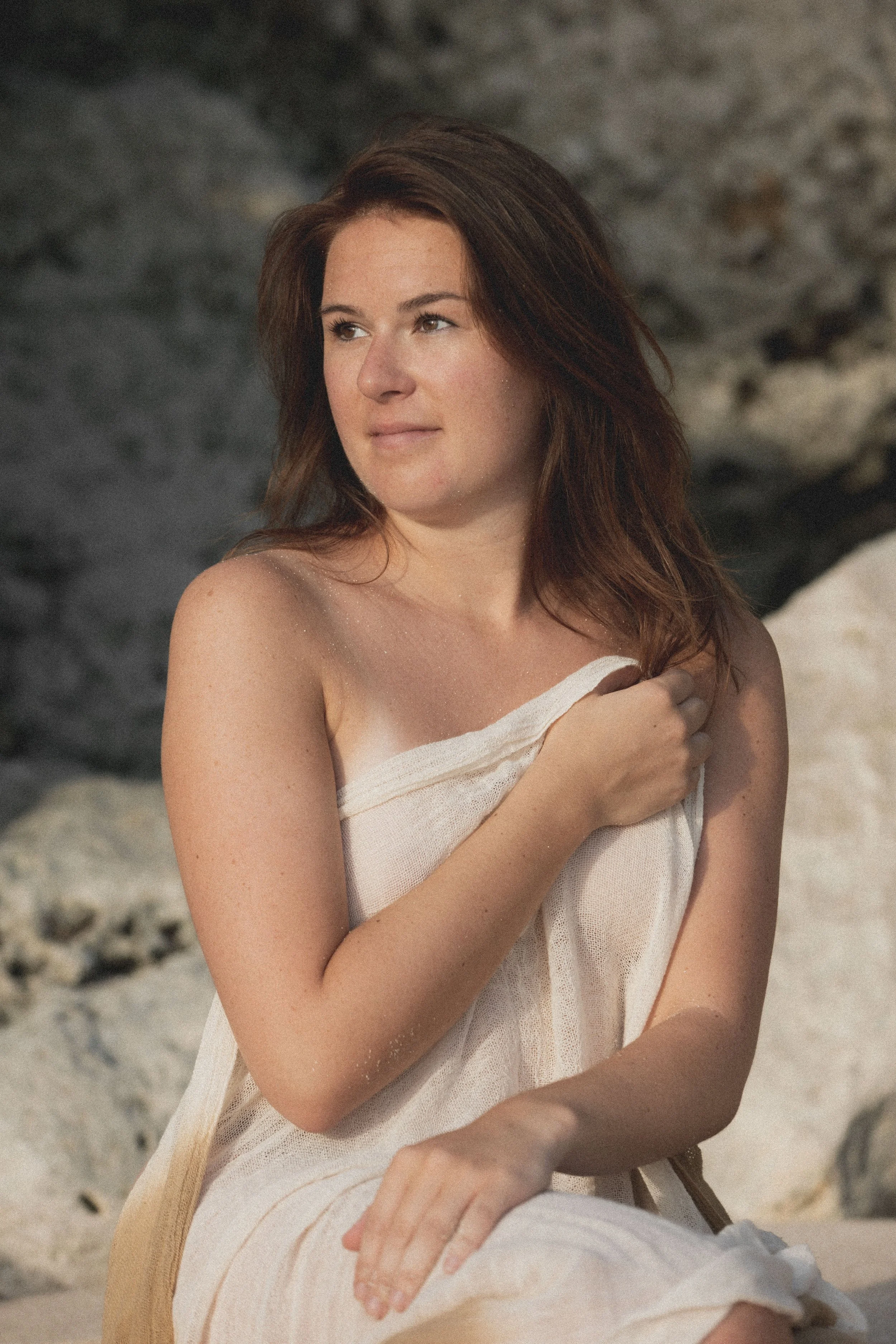portrait of a woman on the beach, covered in a sarong, looking into the distance