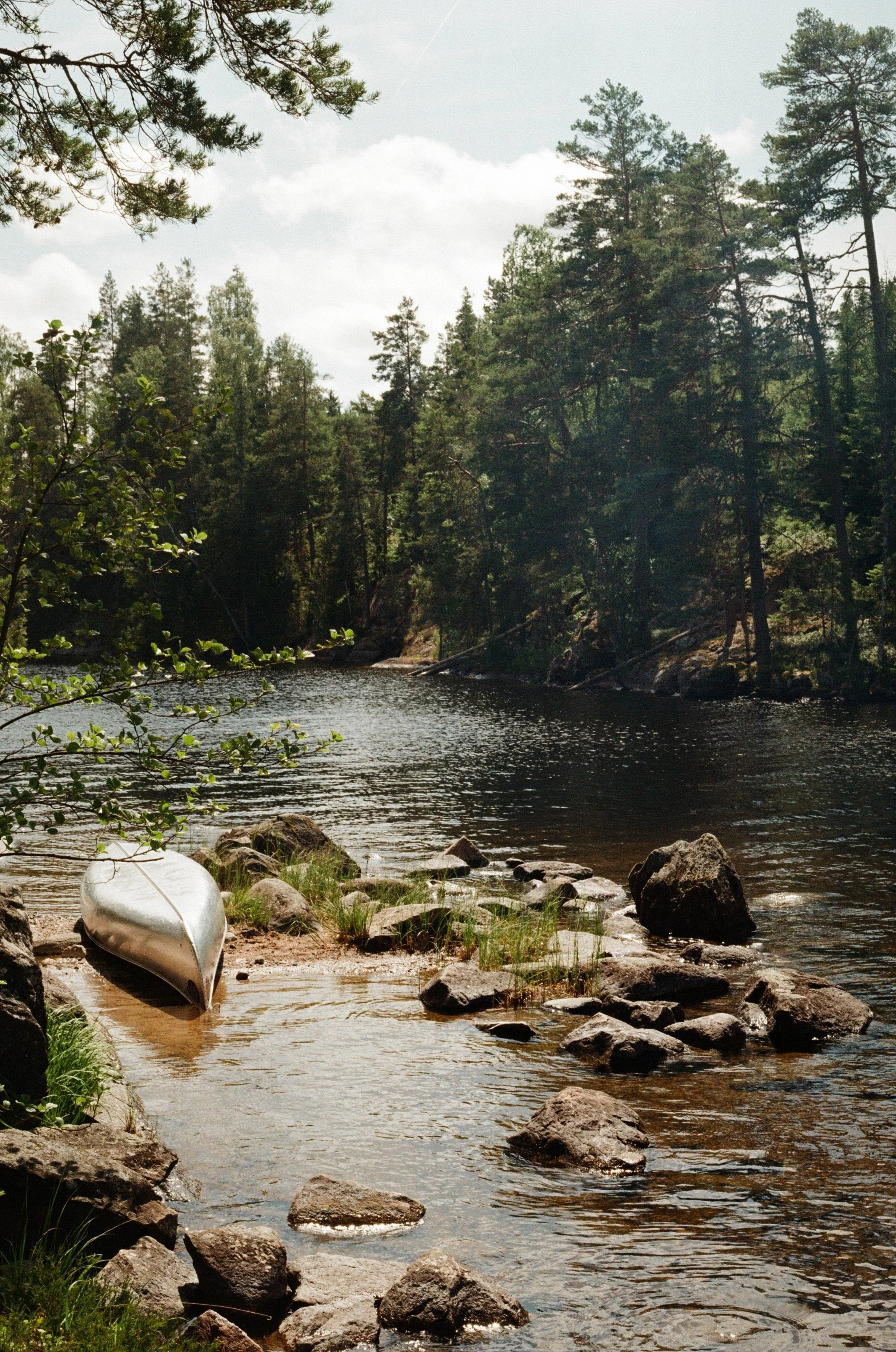 upside canoe on rocks on the side of a river