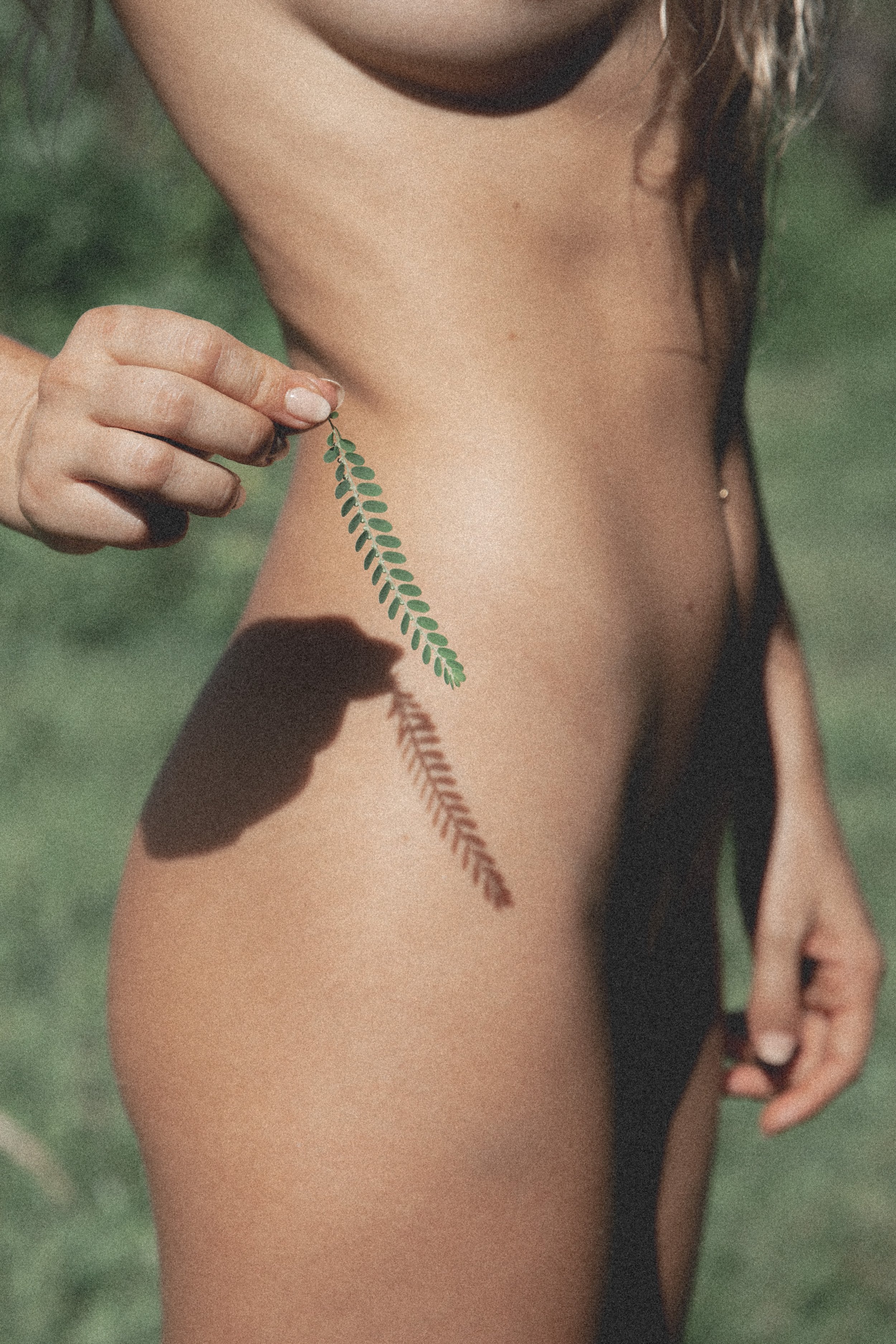 woman holding a leaf in front of her body which creates a shadow of the leave