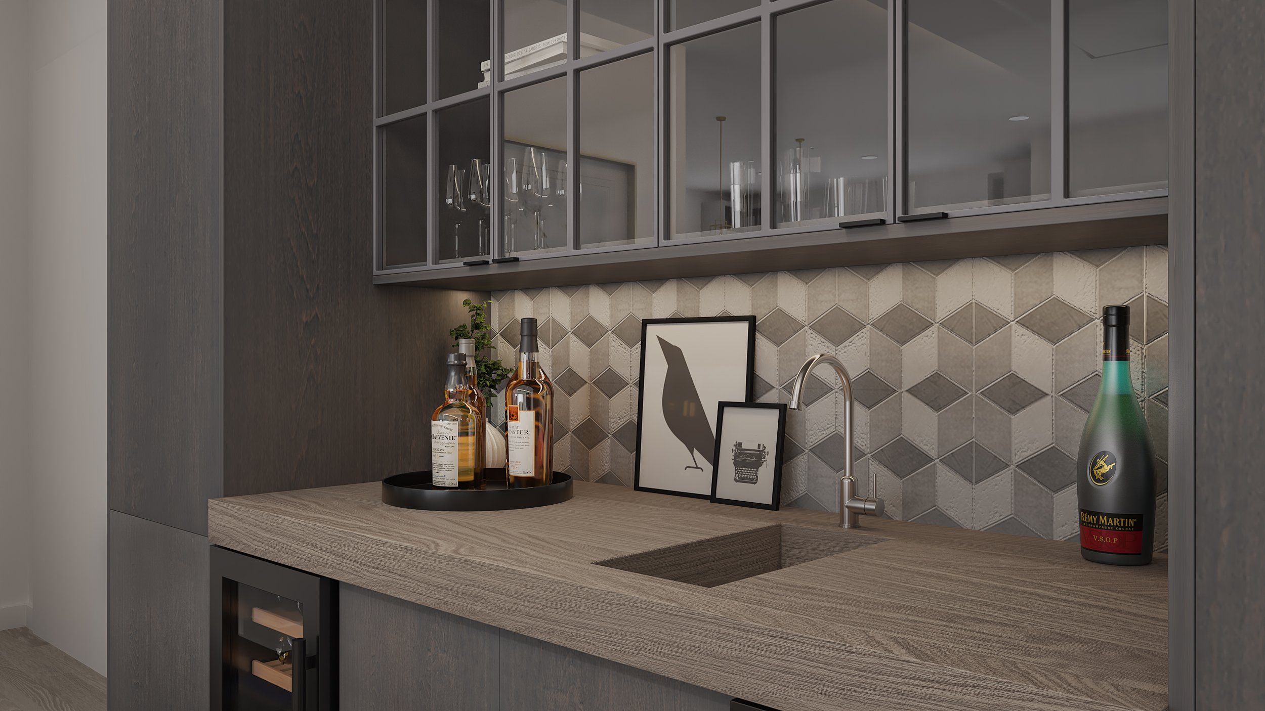 A modern wet bar with a light wood countertop and dark cabinets, featuring a small sink, framed art prints of a bird. The backsplash is beige and gray geometric tiles.