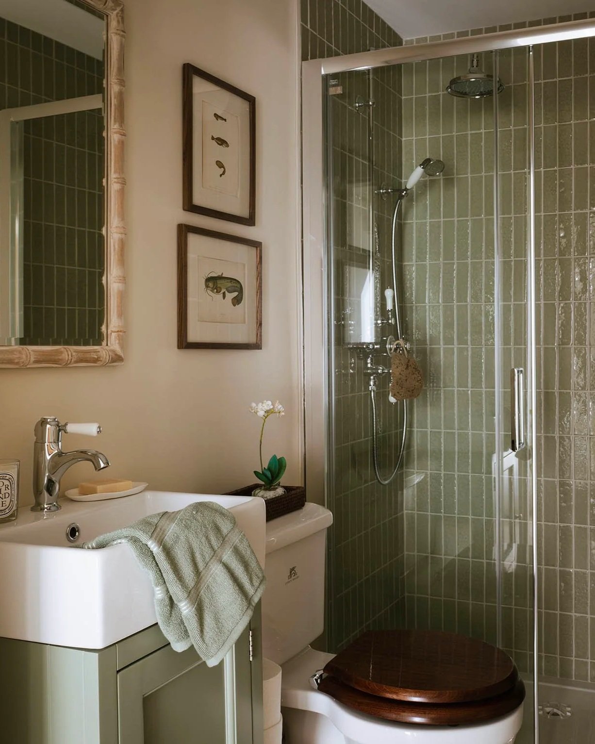 Compact luxury shower room in Woking, Surrey home featuring sage green vertical tile, walk-in glass shower, white vanity, and bamboo mirror.