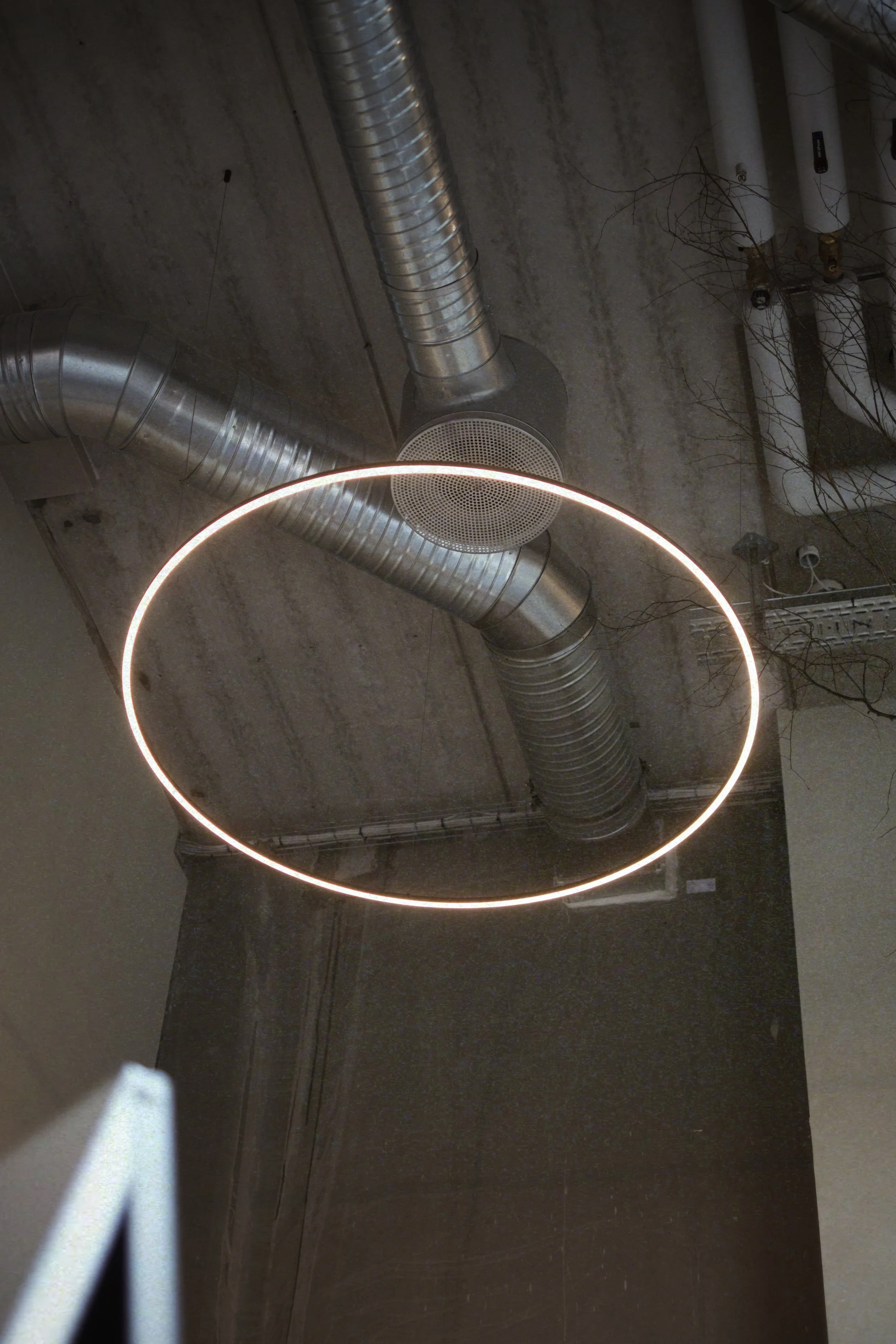 Ceiling with exposed metallic ductwork and a circular LED light fixture.