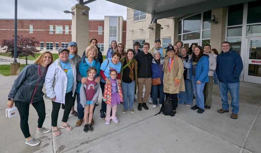 A group of five Boy Scouts in uniform standing behind a table with donuts, coffee pots, and other snacks in a break room or kitchen area.