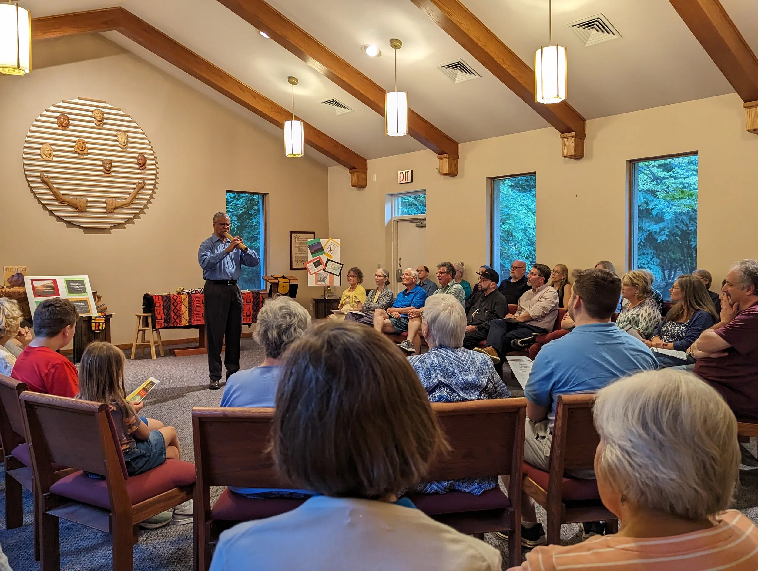 A person playing a flute to a room full of people