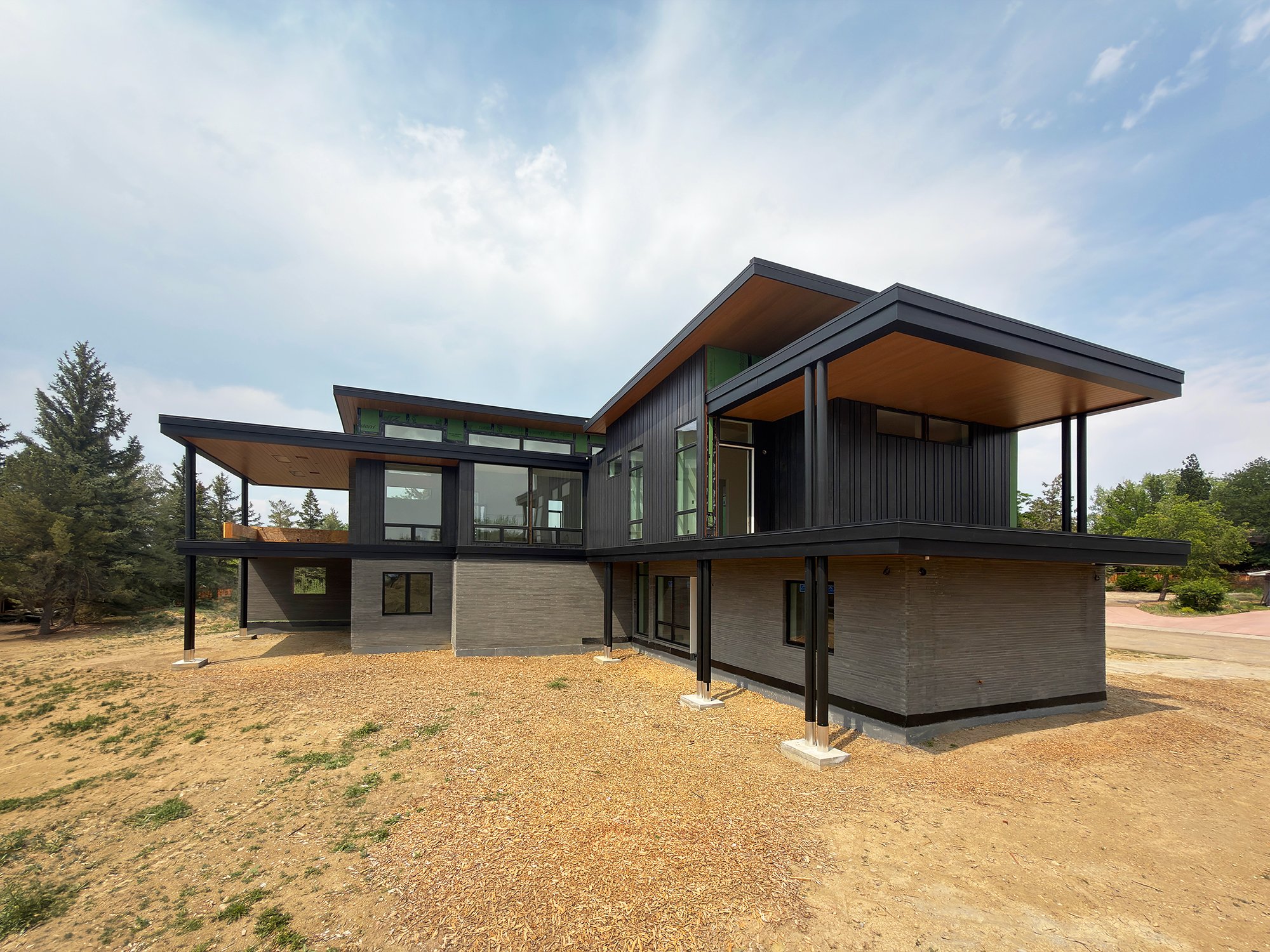 Rear elevation of a contemporary home under construction with steel supports and large cantilevered roof structure in Boulder County Colorado -Designed by Sopher Sparn Architects 
