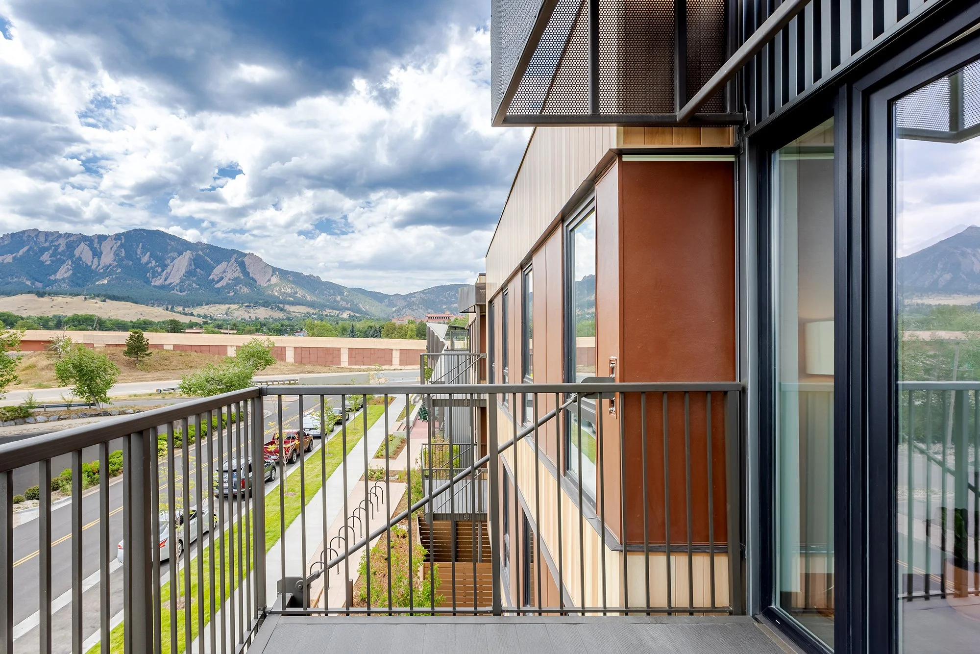 HUB 28th Street private balcony featuring metal railings, wood-toned exterior panels, and views toward the Flatirons.