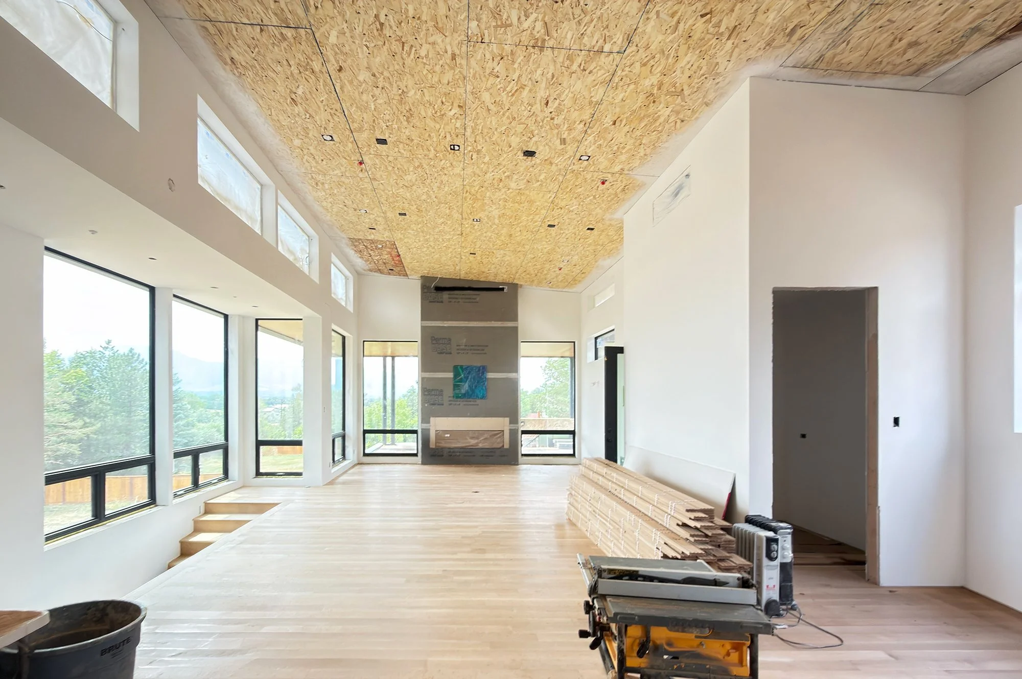Interior main living space showing exposed wood ceiling, windows, and mountain views beyond -Designed by Sopher Sparn Architects