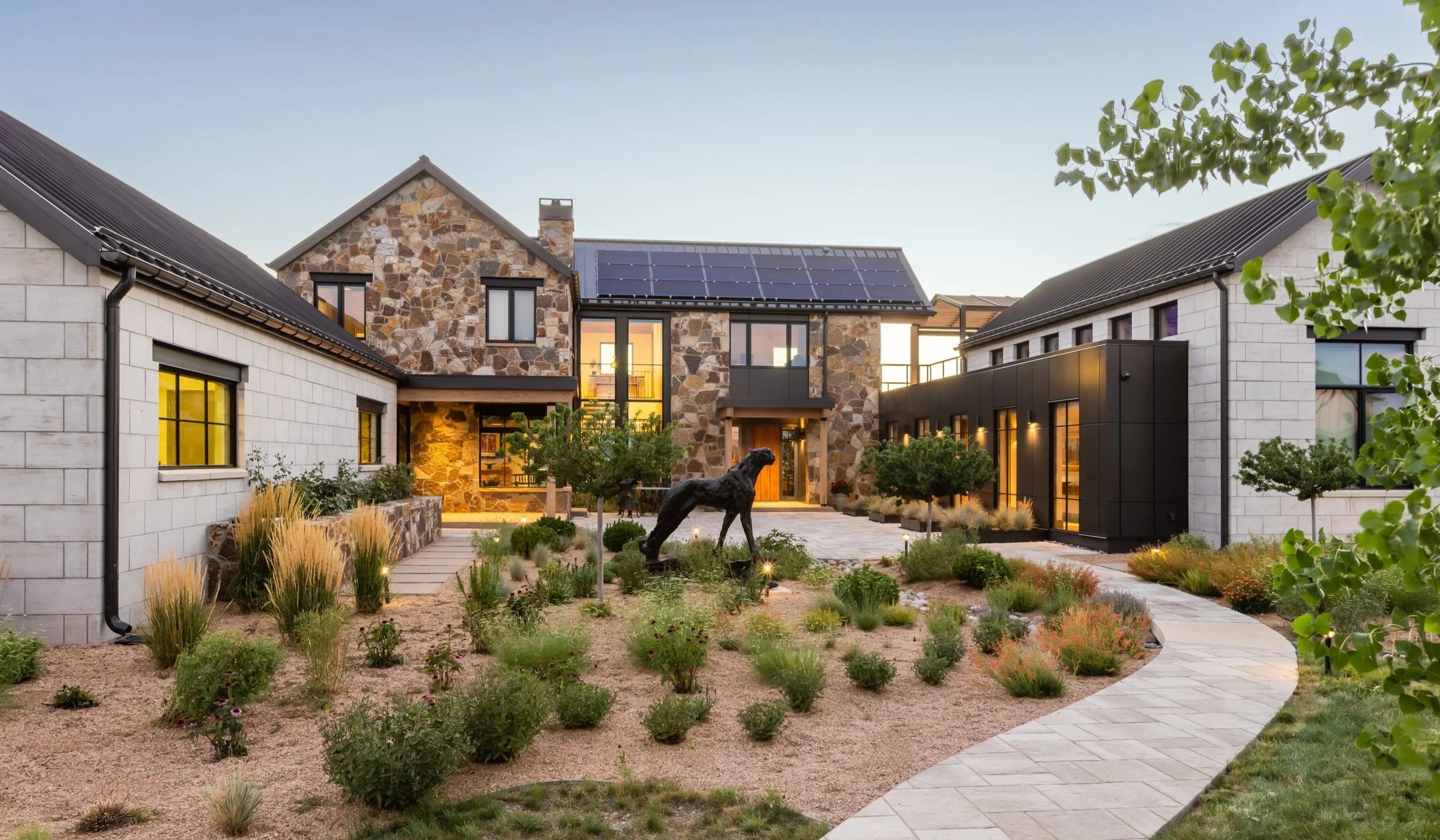 Front exterior of the Eagles Crossing residence in Boulder County, Colorado, featuring stone and limestone façade, large windows, and solar panels on the roof, with landscaped garden and pathways.
 – Designed by Sopher Sparn Architects LLC