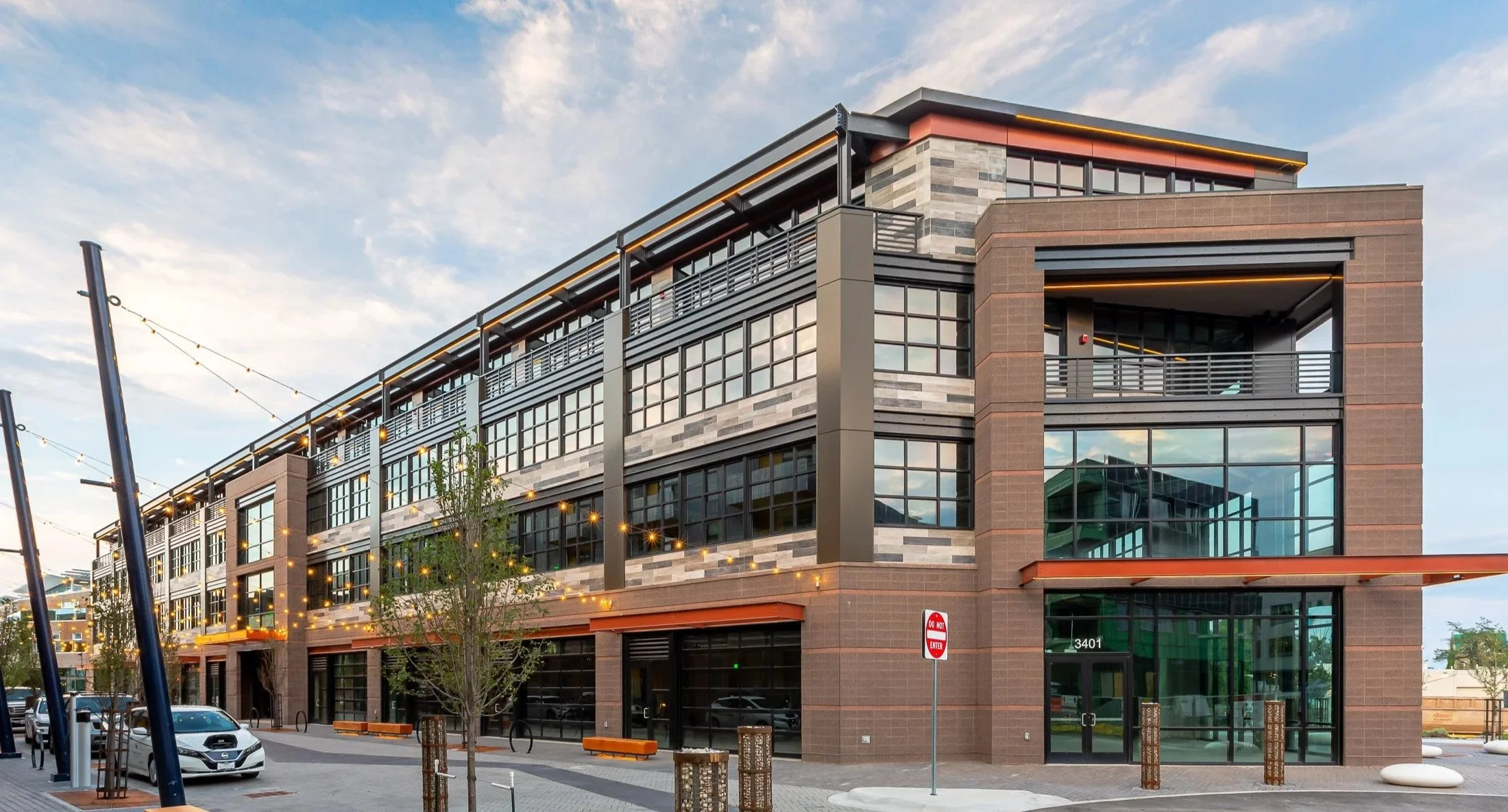 S’PARK Railyards in Boulder, CO, corner view of the multi-story commercial building with large glass windows, brown exterior panels, street-level retail spaces, and balconies above.
-Designed by Sopher Sparn Architects 