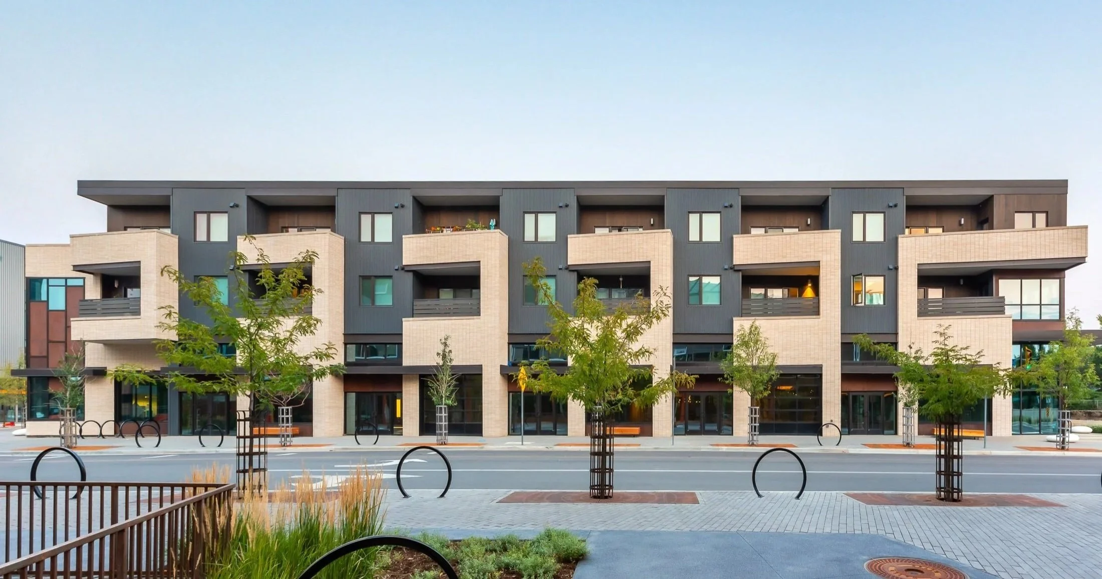 S’PARK Ciclo in Boulder, CO – Modern multi-story apartment building with sidewalk, street trees, and bike racks in front, highlighting pedestrian-friendly design. Designed by Sopher Sparn Architects.