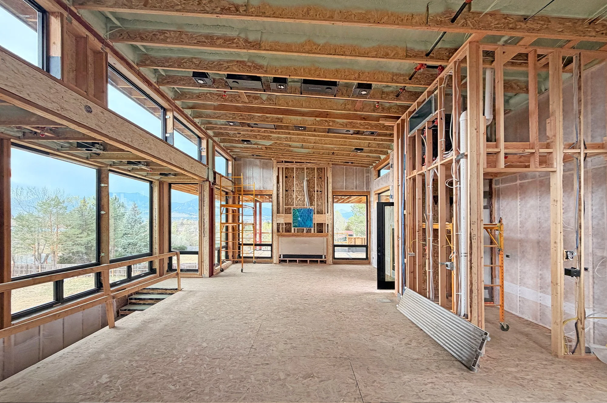 Interior framing of main living space showing exposed wood structure, window openings, and mountain views beyond -Designed by Sopher Sparn Architects