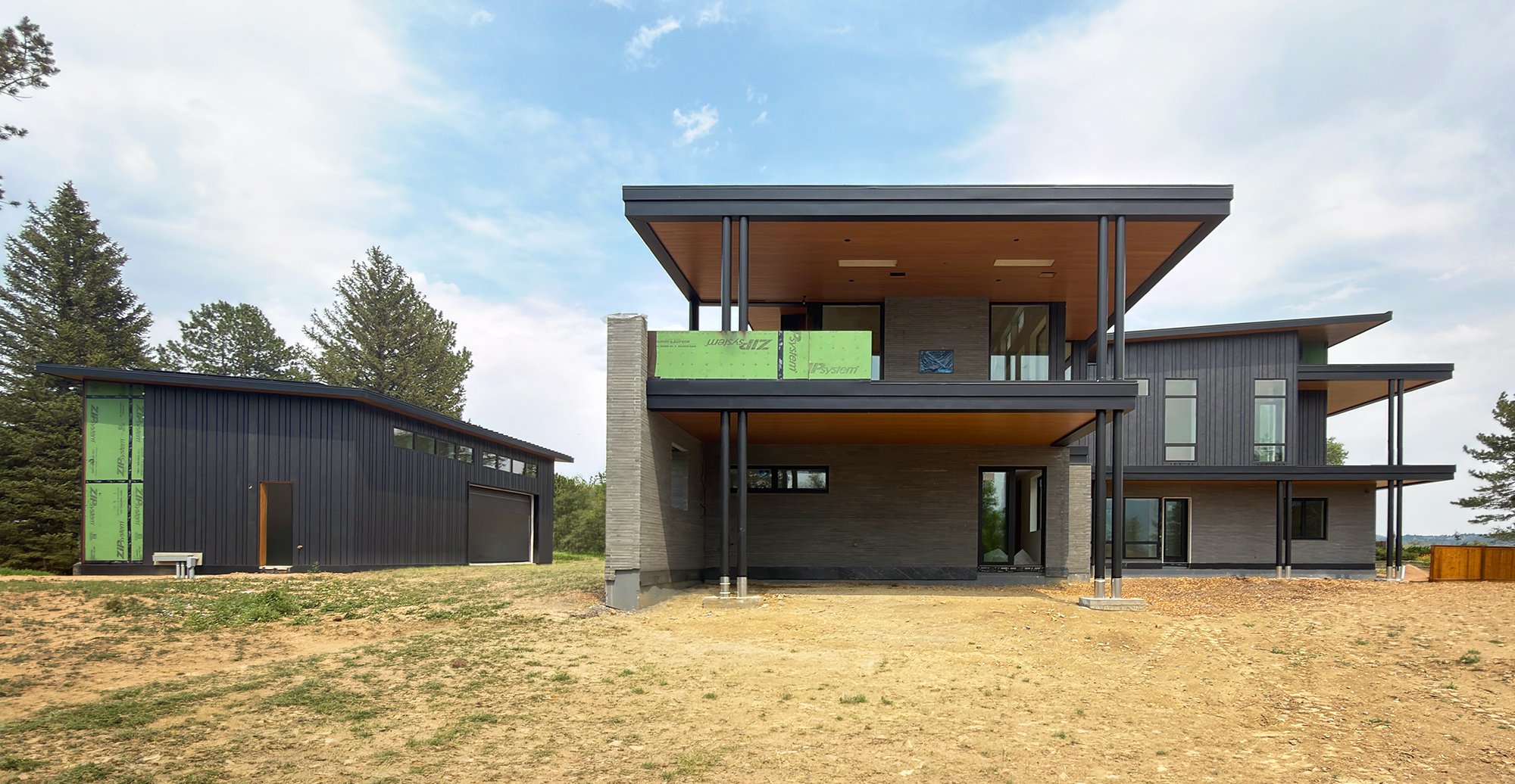 Rear elevation of a contemporary home under construction with steel supports and large cantilevered roof structure in Boulder County Colorado -Designed by Sopher Sparn Architects 