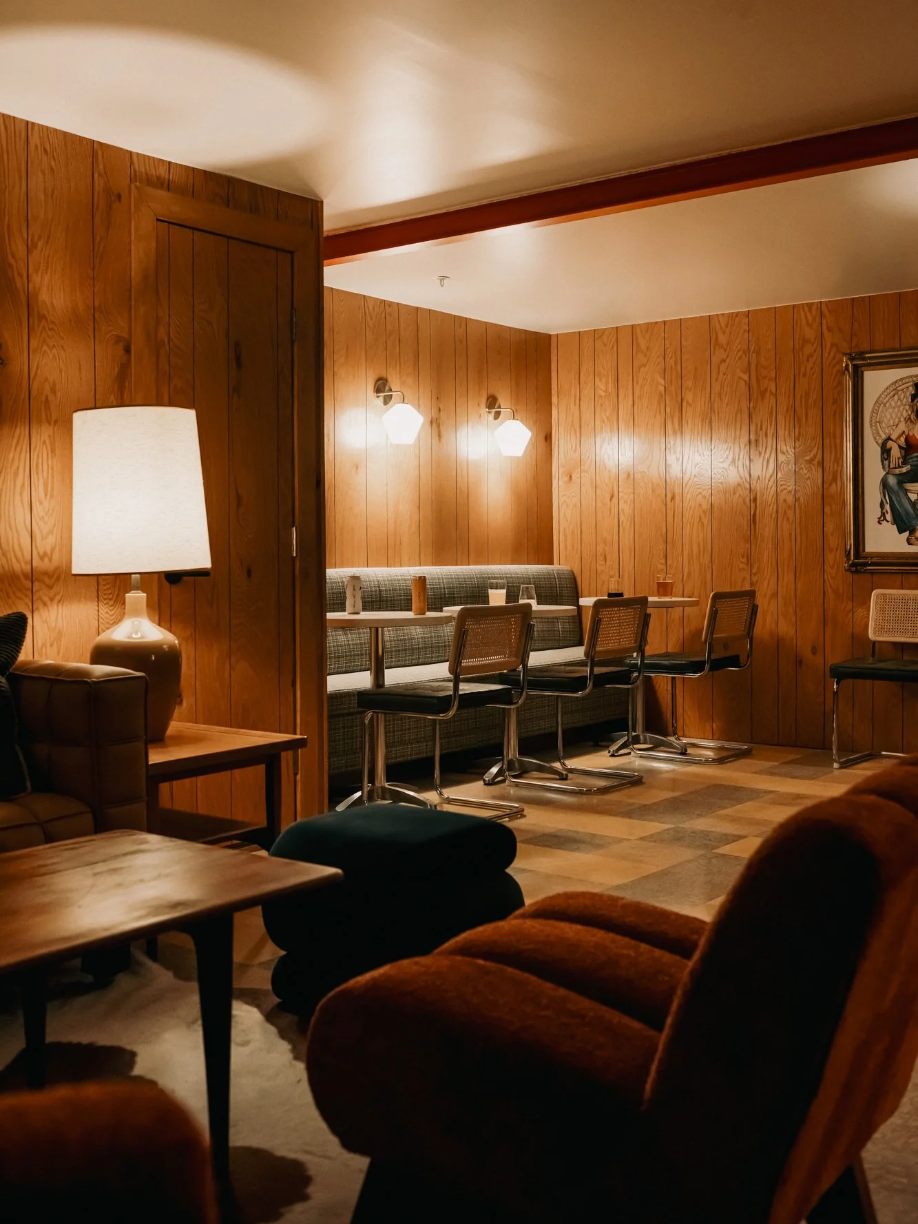 Lounge area at La Vista Motel in Denver, CO with seating, lamps, and wood panel accents.
