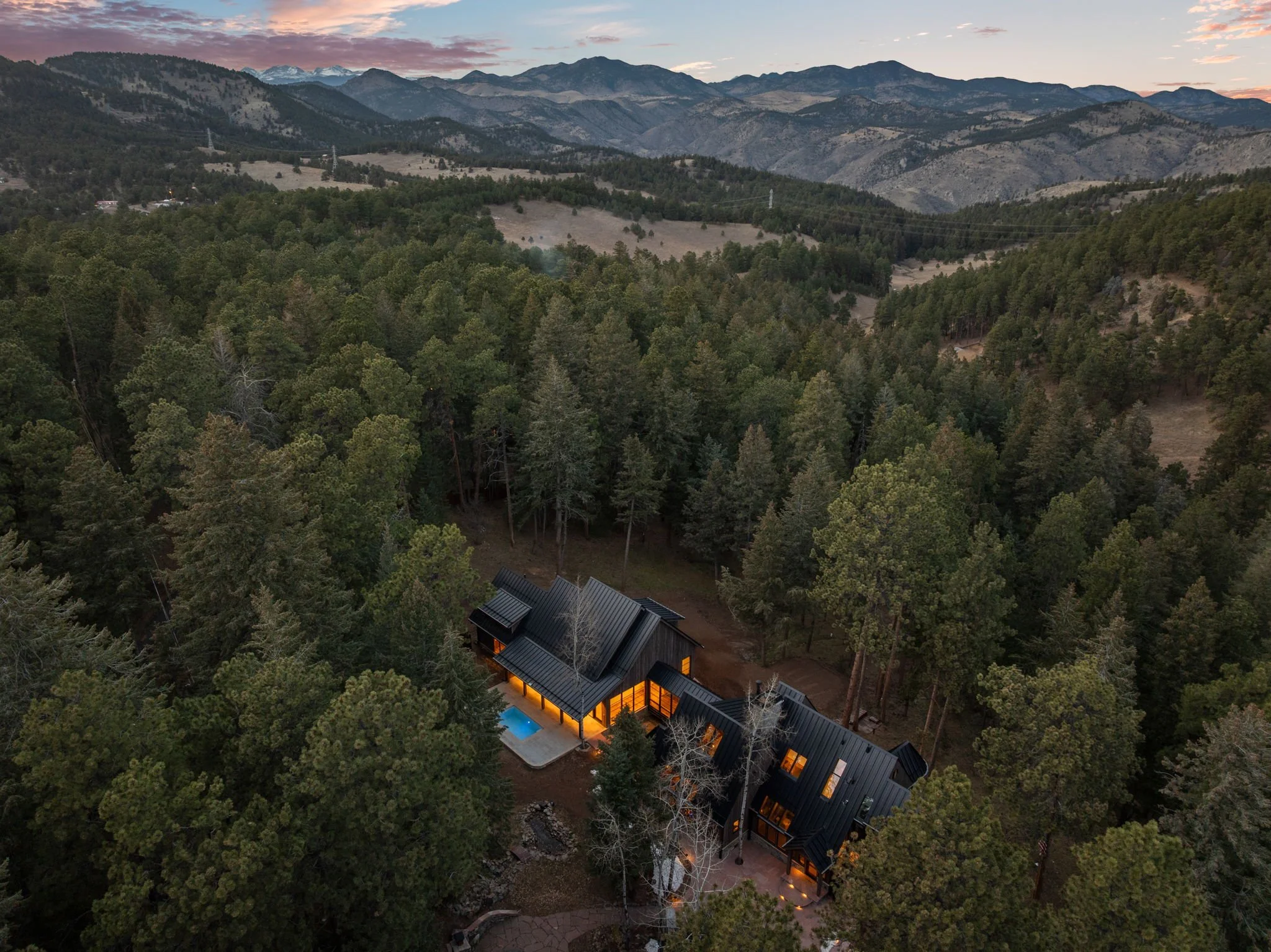 Aerial view of the Cedar & Stone residence in Jefferson County, Colorado, showing mountain home with pool and landscaped grounds at sunset.