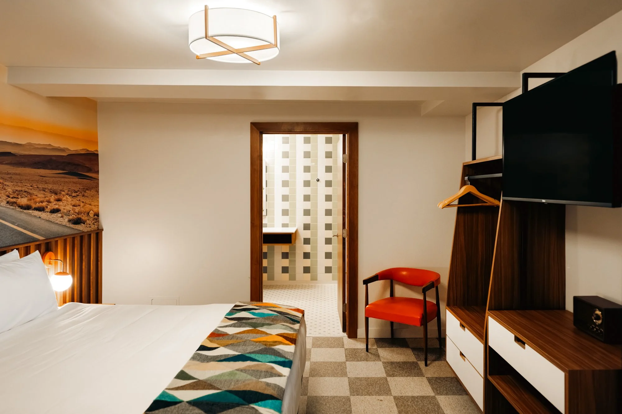 Bedroom interior at La Vista Motel in Denver, CO featuring a queen bed, patterned bedding, and modern furnishings.
