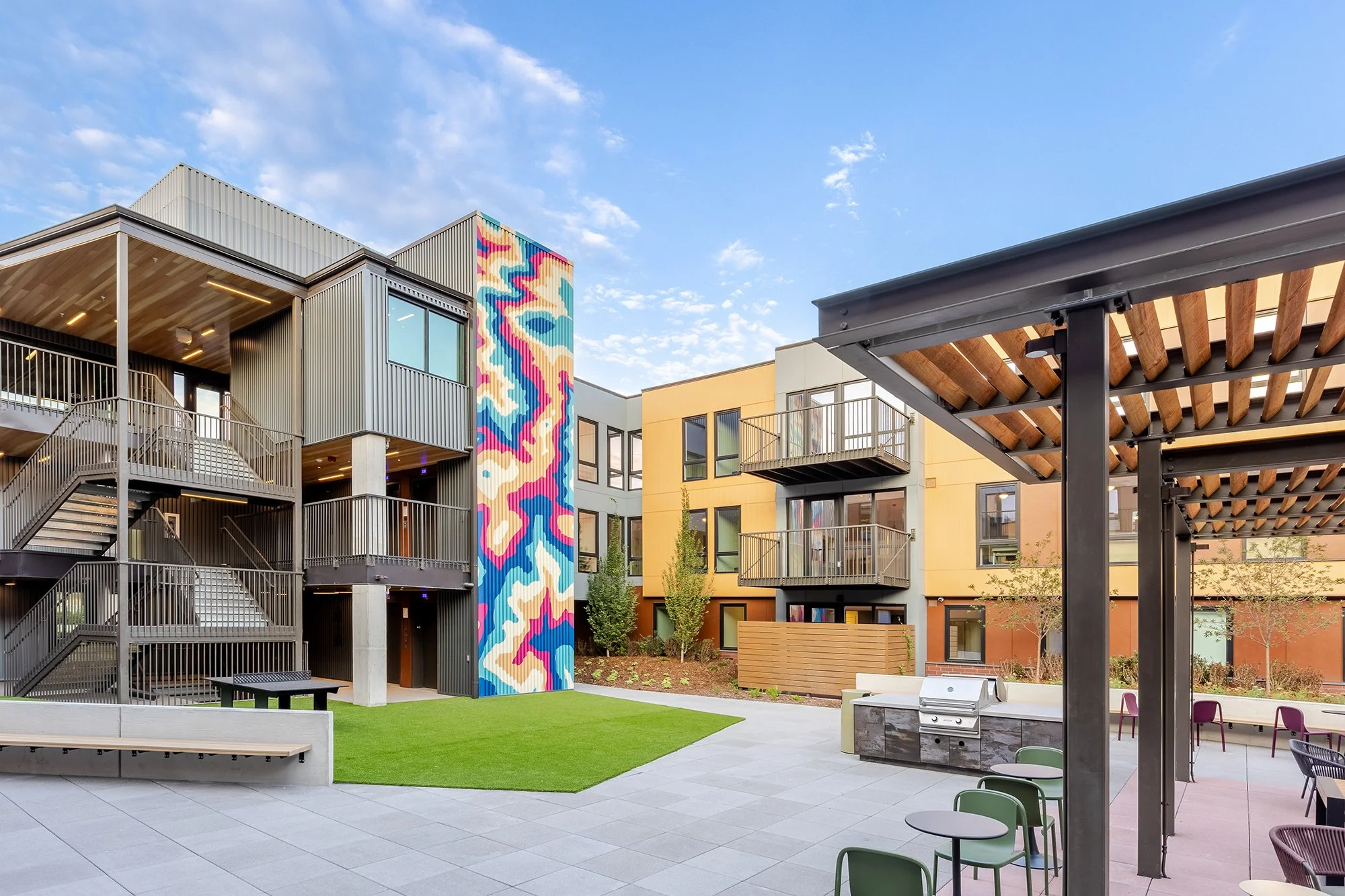 HUB 28th Street courtyard with colorful mural artwork, residential balconies, landscaping, and outdoor gathering space.
