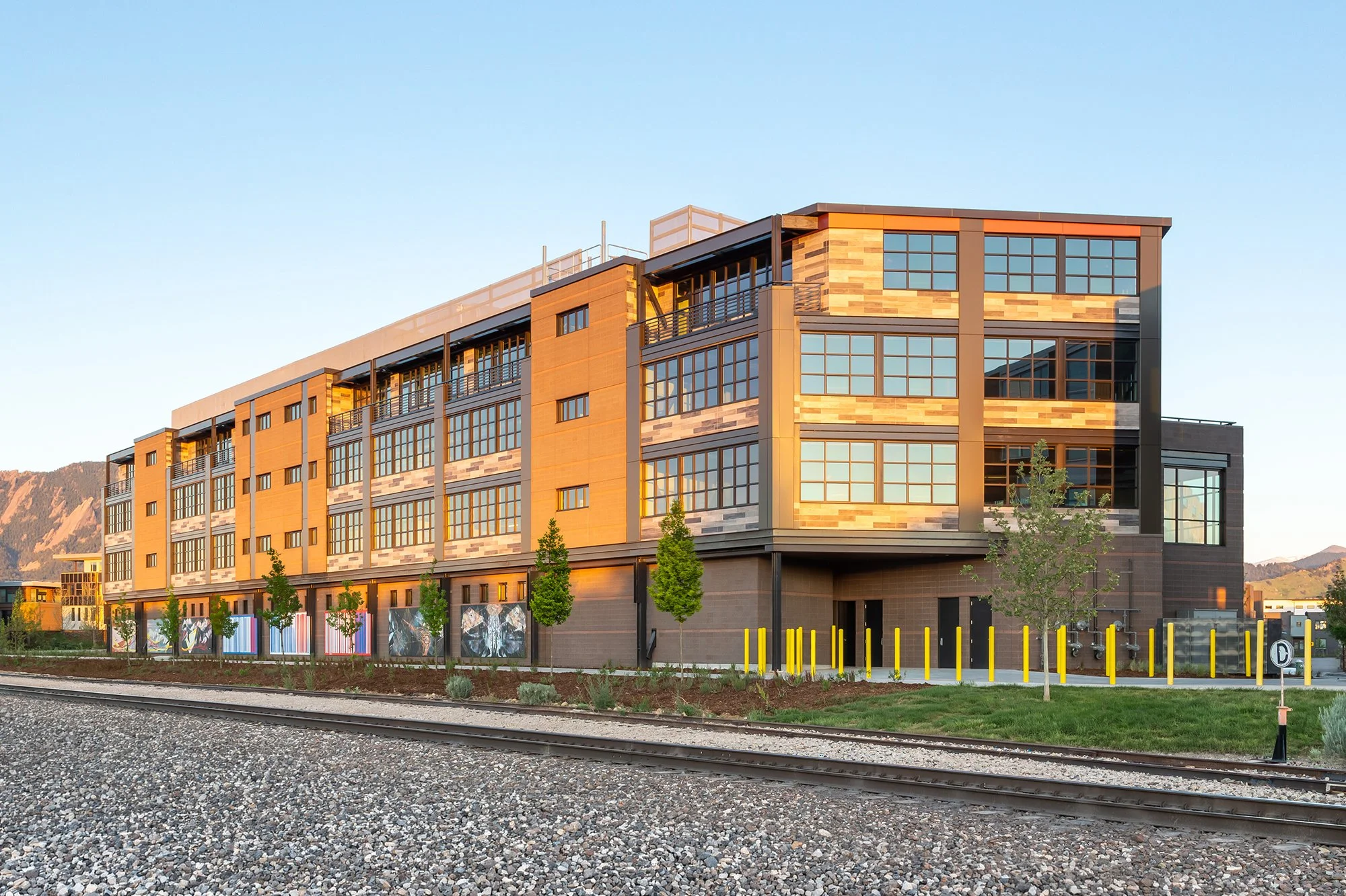 Street-level perspective of S’PARK Railyards, highlighting multi-story building with large windows, mountain views, and outdoor seating.