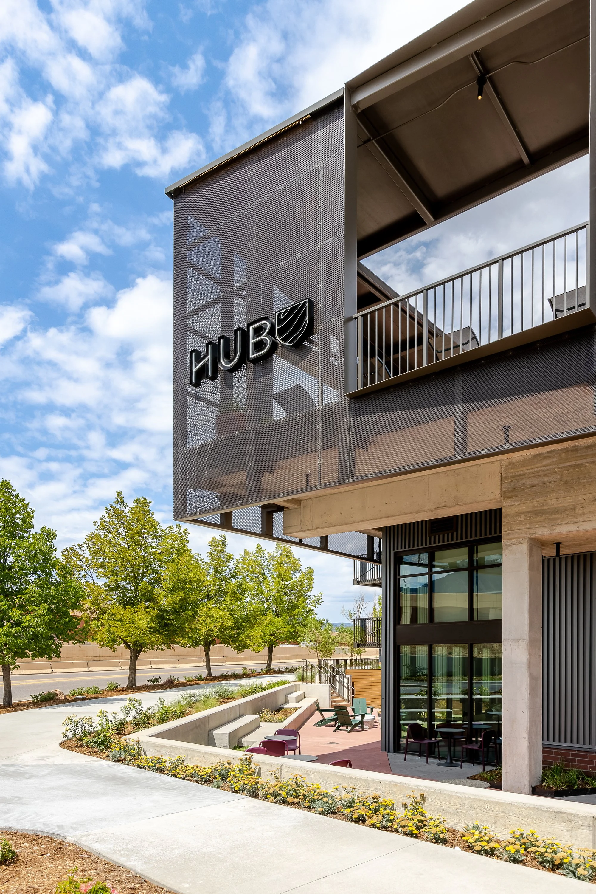 HUB 28th Street exterior featuring a perforated metal screen, rooftop pool deck, and landscaped pedestrian walkway in Boulder, Colorado.