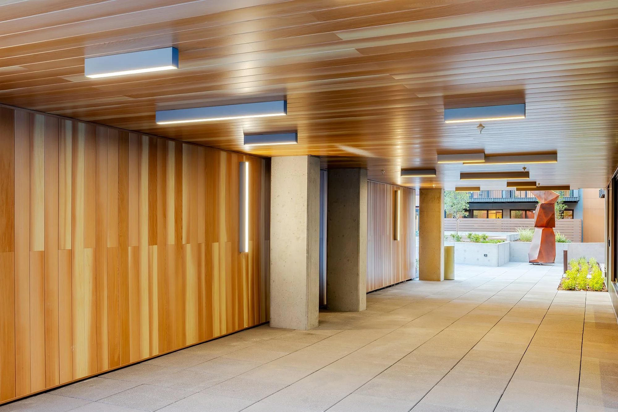 HUB 28th Street interior amenity space featuring a wood slat ceiling, wood wall panels, and contemporary lighting.