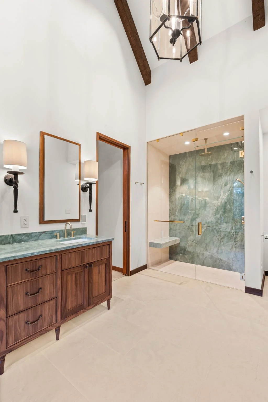 Bathroom at the Cedar & Stone residence in Jefferson County, Colorado, with wood vanity, green marble countertops, and glass-enclosed shower with brass fixtures.