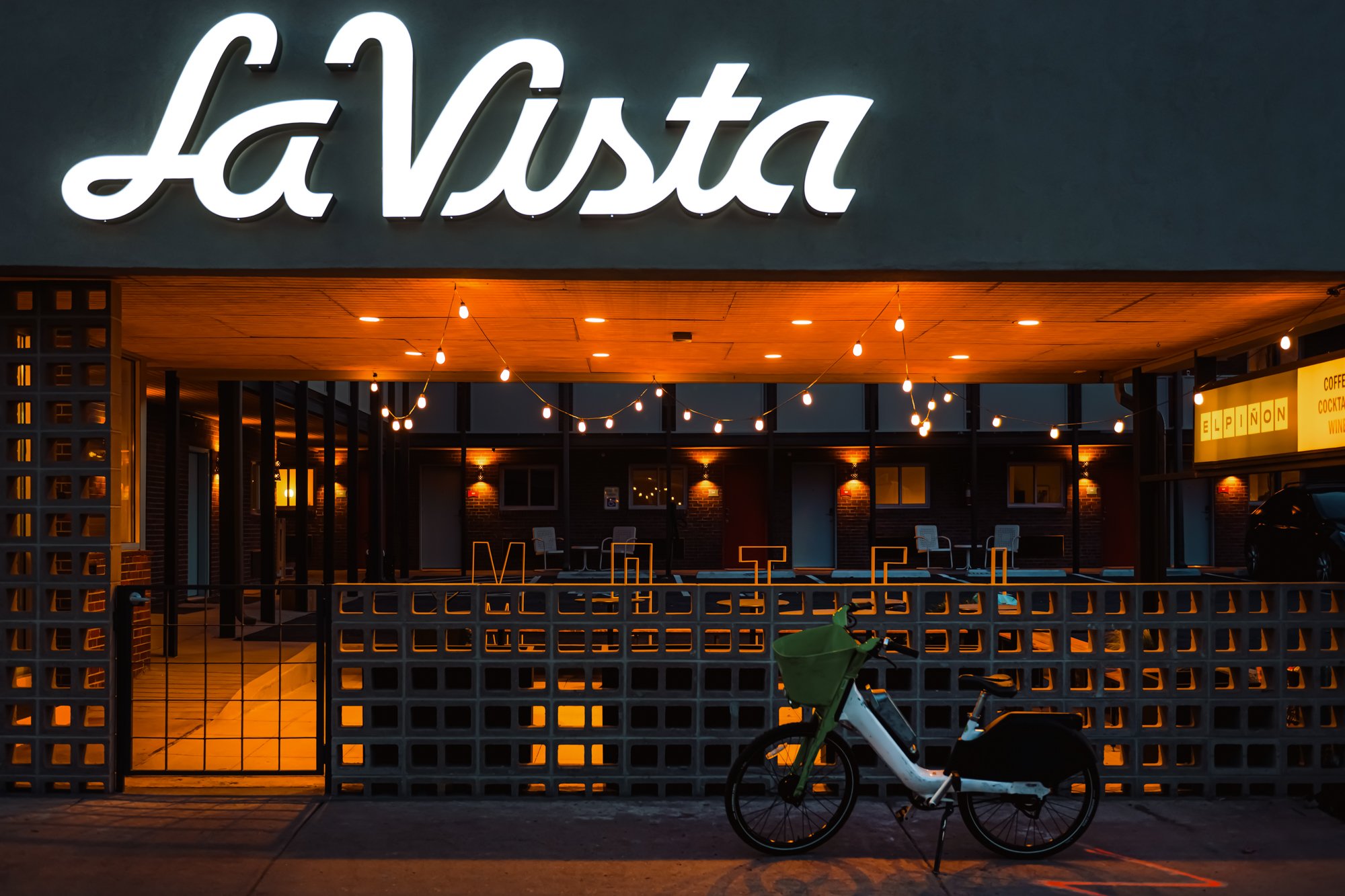 Exterior of La Vista Motel in Denver, CO with illuminated signage and outdoor seating