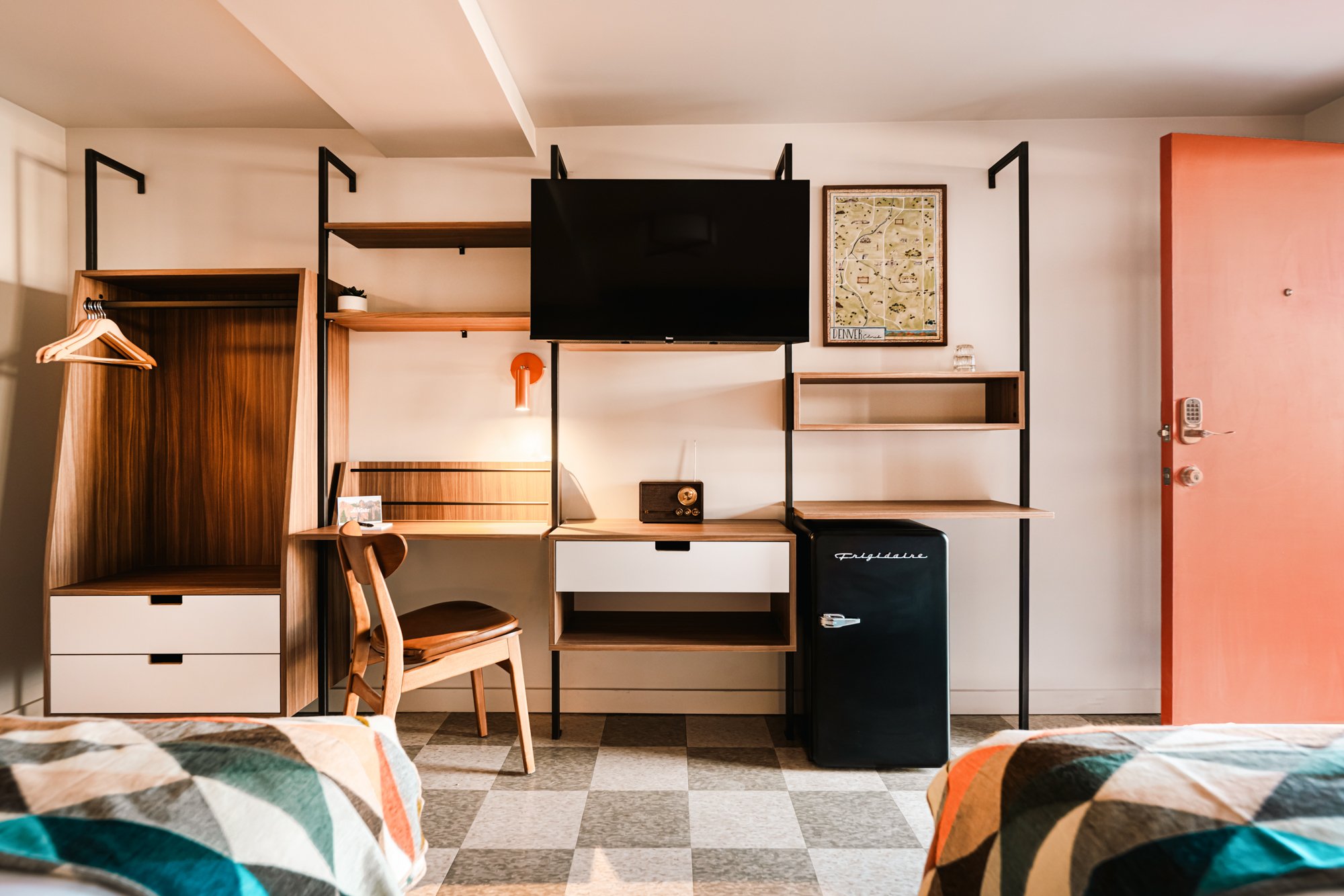 Guest room at La Vista Motel in Denver, CO with bed, desk, shelving, and contemporary furnishings.
