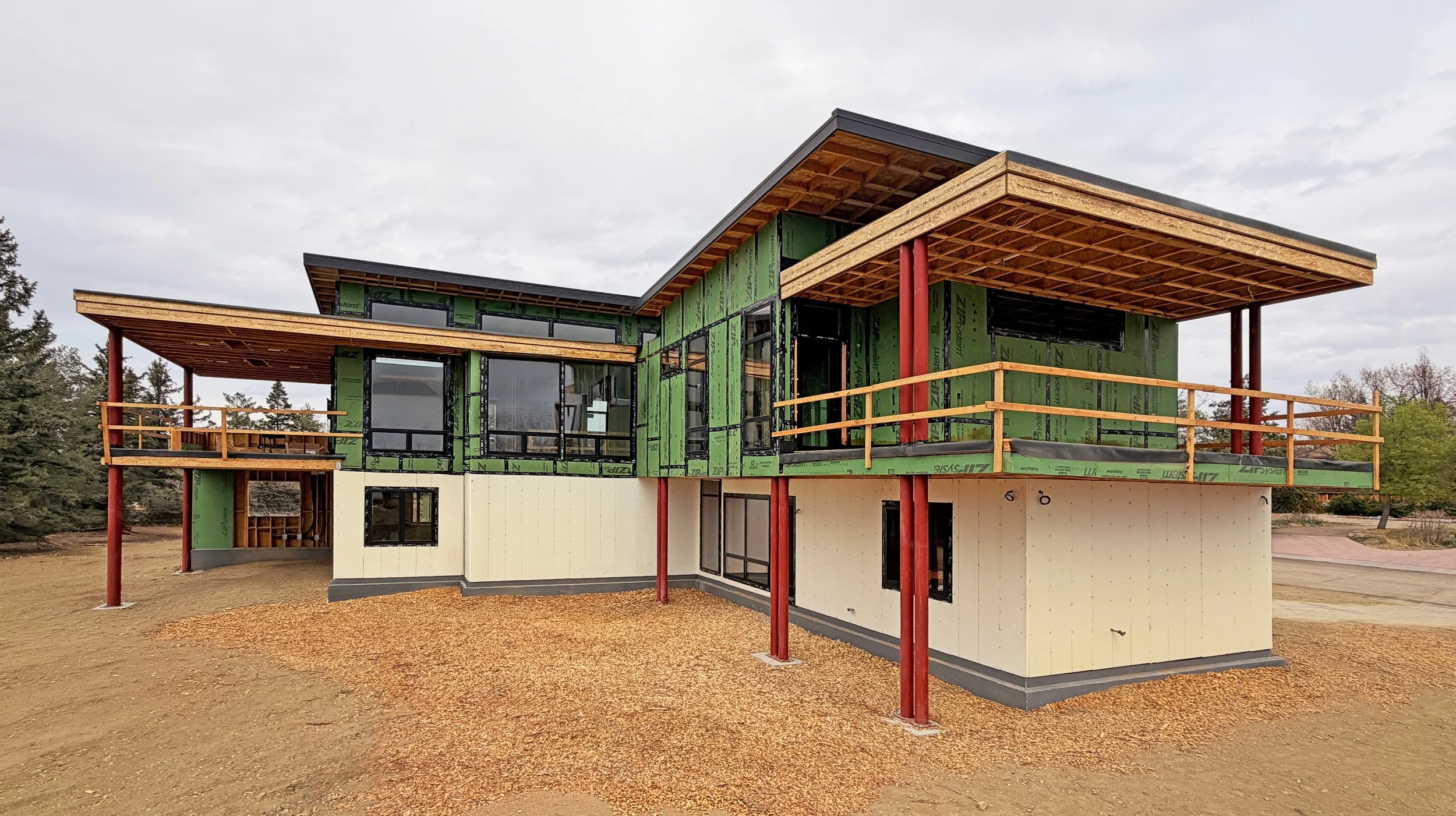 
Framed modern residence with extended roof overhangs and exposed structural columns during construction in Boulder County -Designed by Sopher Sparn Architects