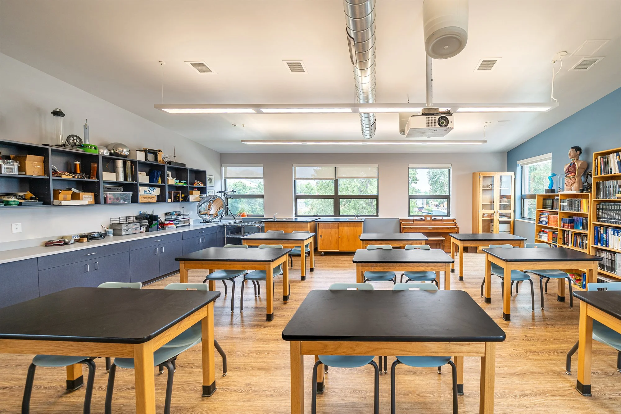 Science classroom at Shining Mountain Waldorf School High School in Boulder, CO, with lab tables, stools, large windows, and natural light illuminating the space.
