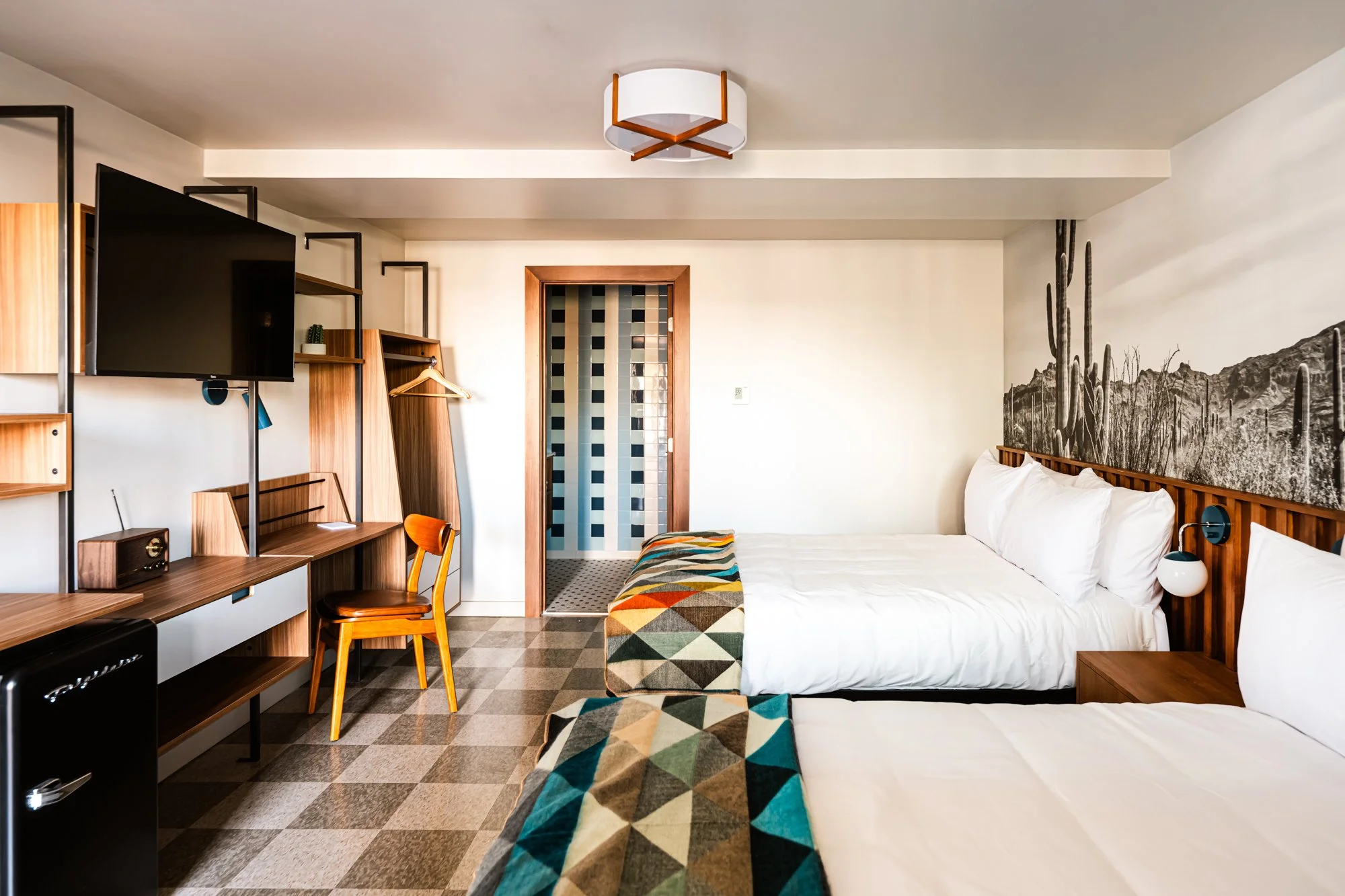 Bedroom view at La Vista Motel in Denver, CO showing a bed, desk, and natural light from large windows.