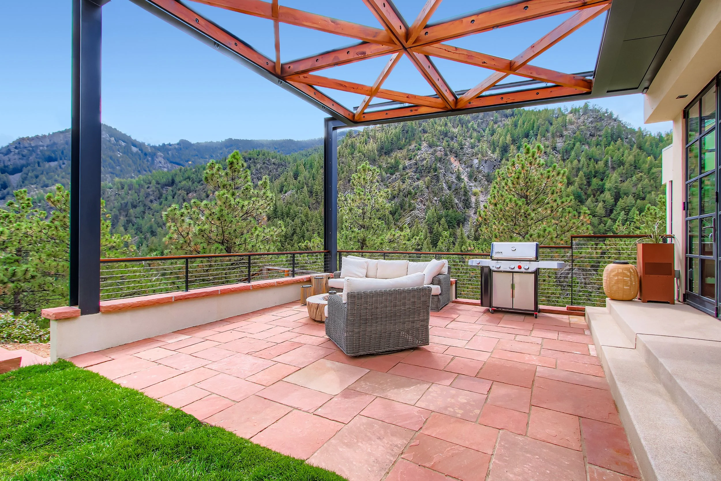 Outdoor patio at Onyx Ridge, Boulder County, CO, with modern seating, barbecue grill, and views of surrounding mountains.