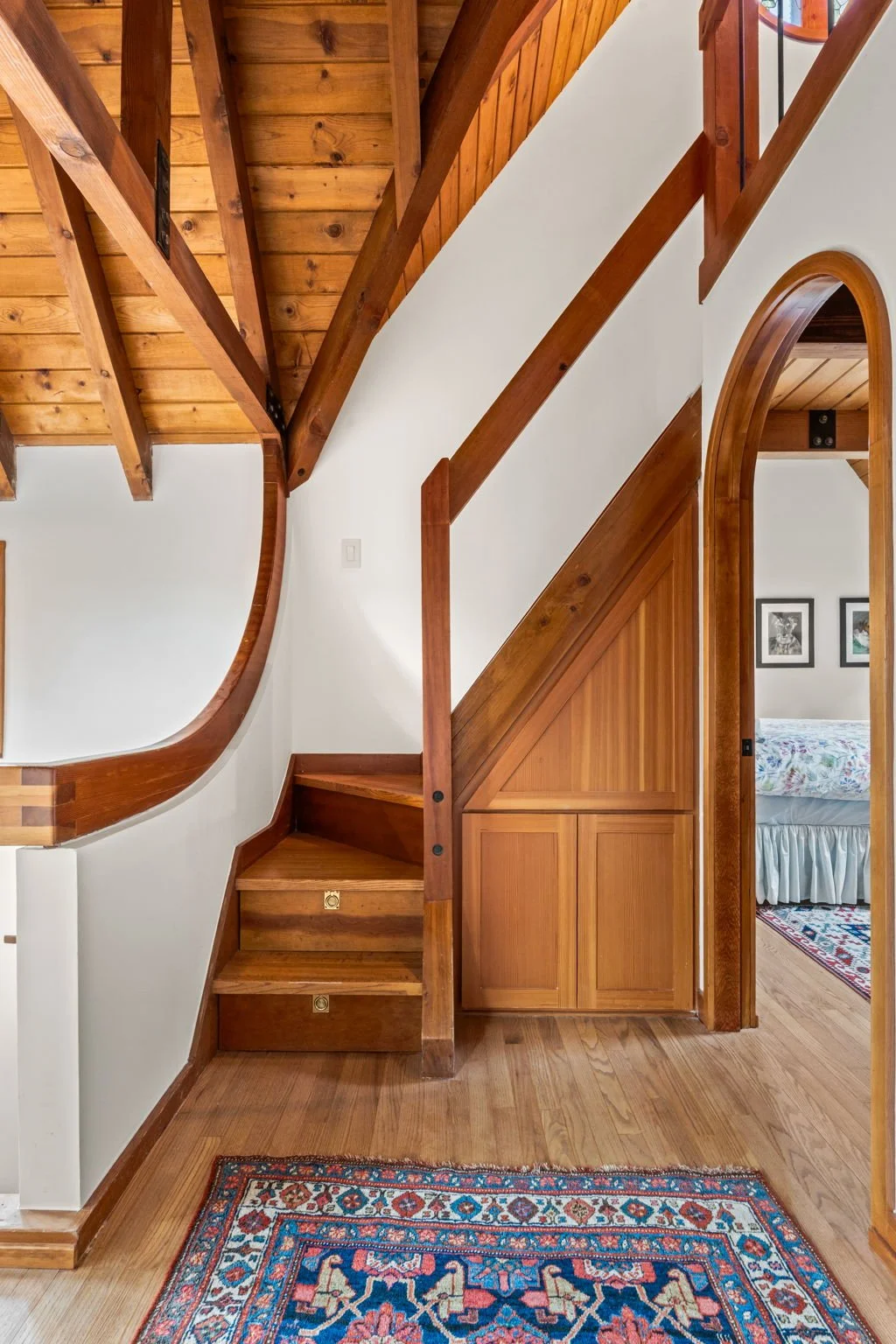 Interior staircase at the Cedar & Stone residence in Jefferson County, Colorado, with wood steps and arched doorway leading to adjacent room.