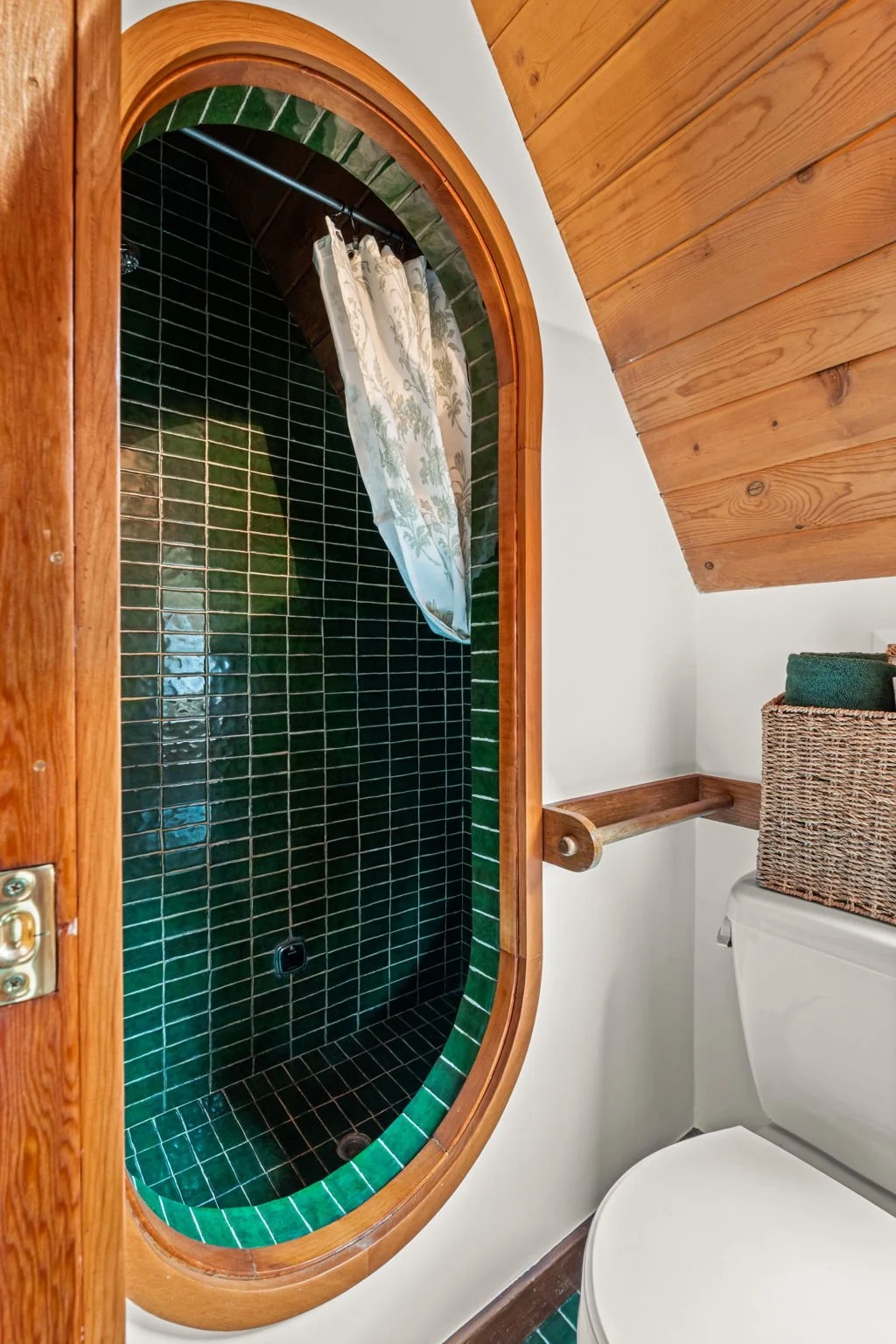 Bathroom at the Cedar & Stone residence in Jefferson County, Colorado, with green tile shower and oval wood-framed opening.