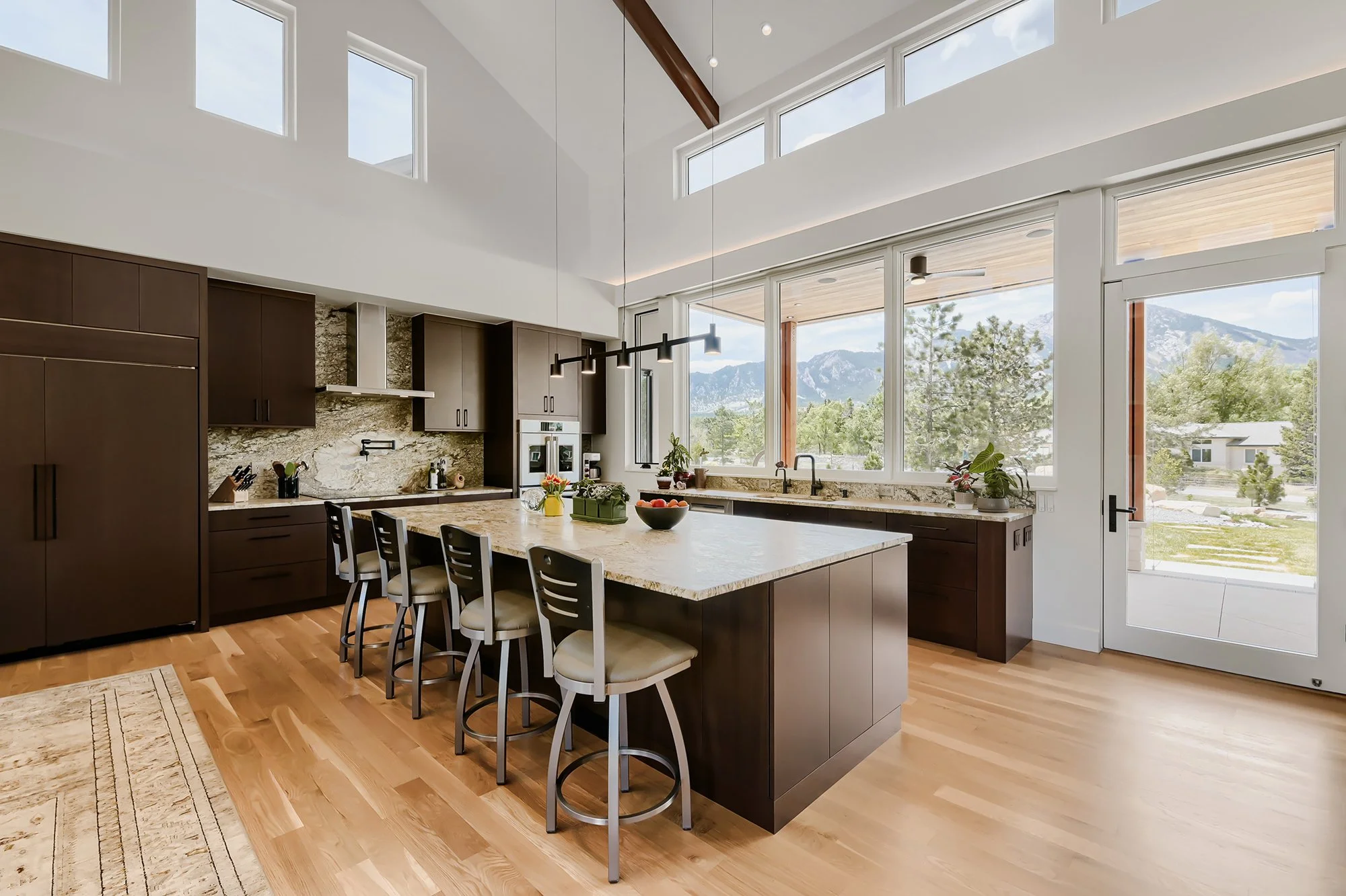 Contemporary kitchen and dining area with exposed wood beams, large island, and abundant natural light.