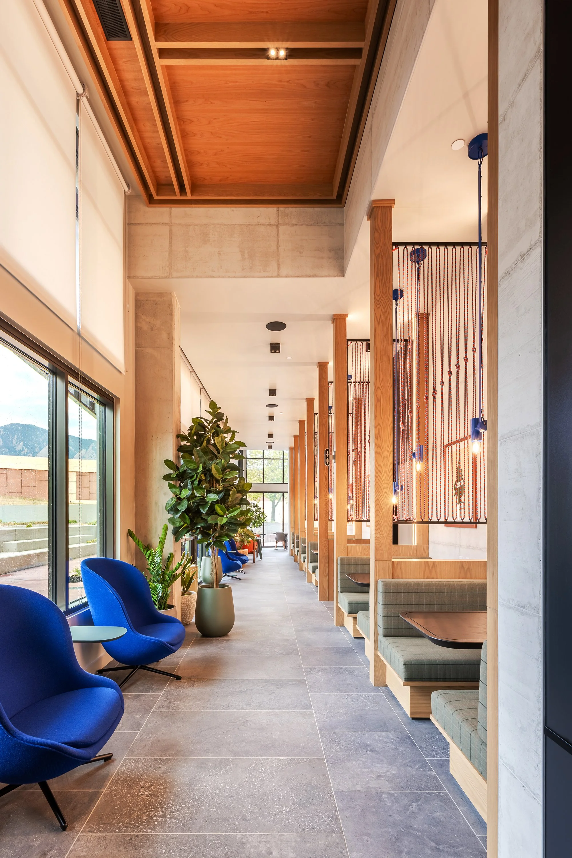 HUB 28th Street interior lounge with wood wall detailing, built-in seating, large windows, and natural light.