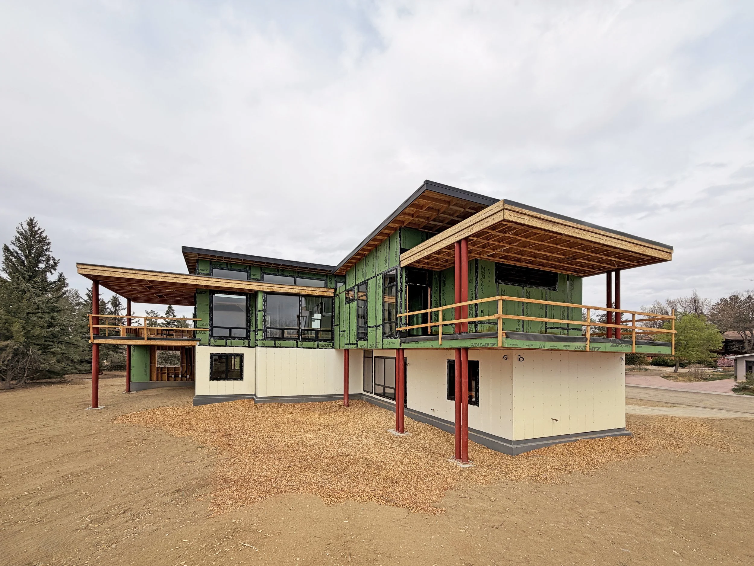 Rear elevation of a contemporary home under construction with steel supports and large cantilevered roof structure in Boulder County Colorado -Designed by Sopher Sparn Architects 