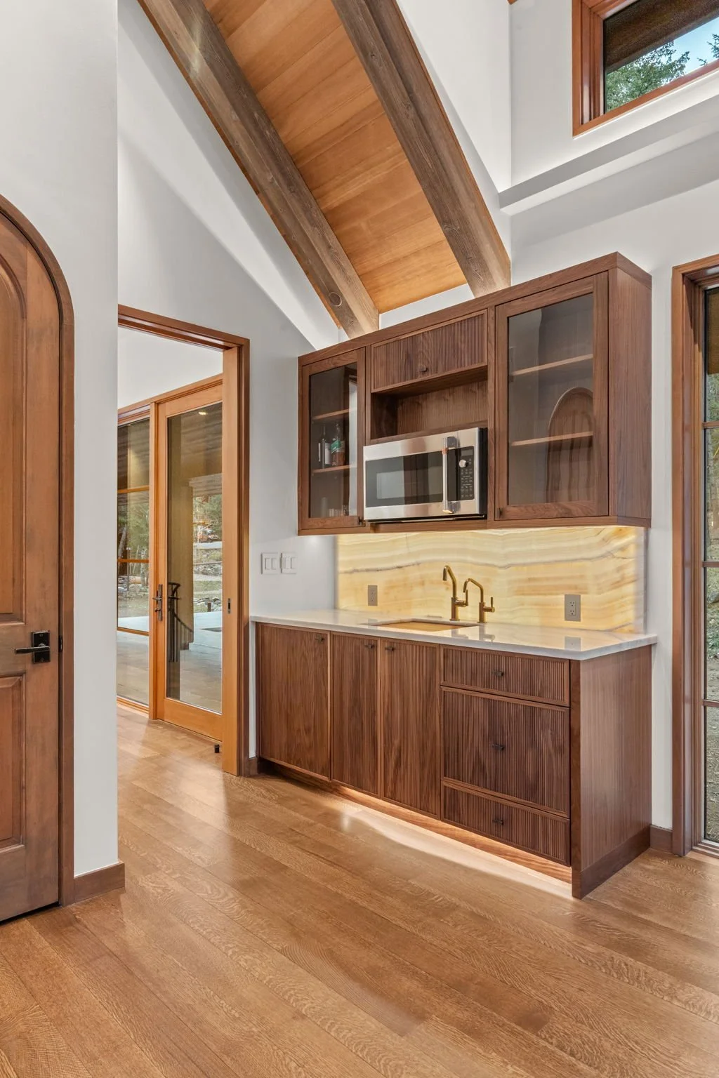 Kitchenette at the Cedar & Stone residence in Jefferson County, Colorado, with wood cabinetry, marble countertop, and doors opening to the exterior.