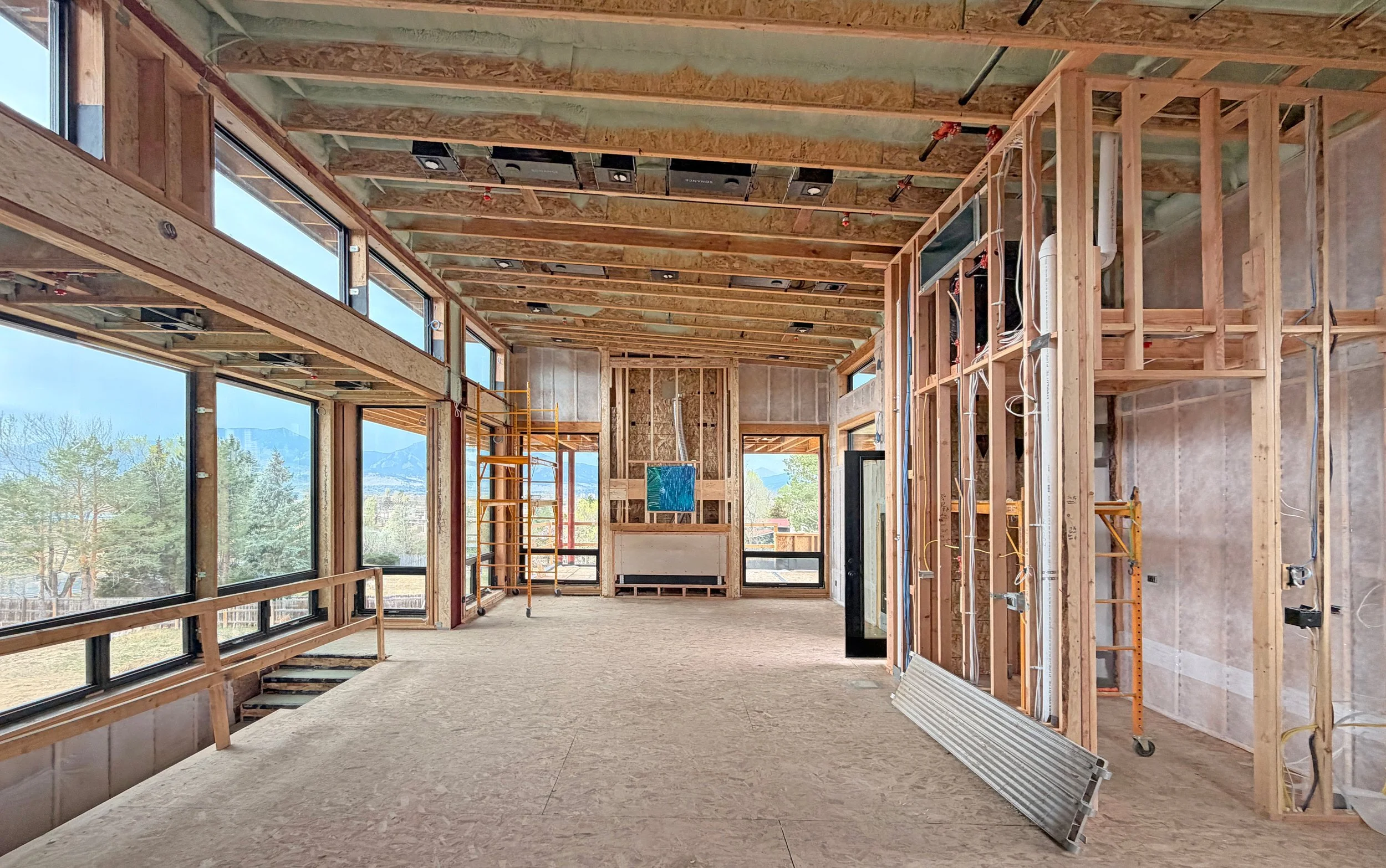 Interior framing of main living space showing exposed wood structure, window openings, and mountain views beyond -Designed by Sopher Sparn Architects