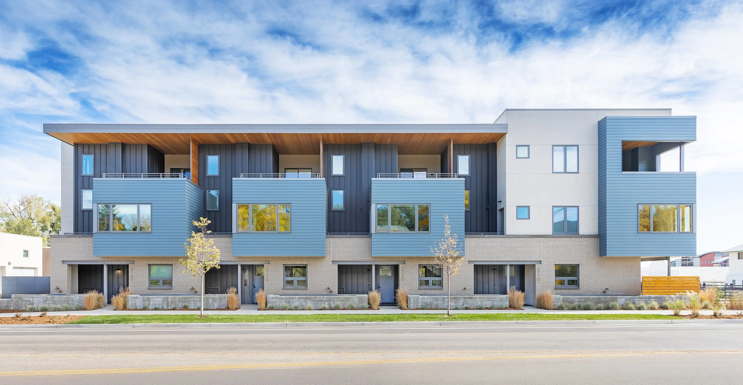 Flatiron Vista residential townhomes in Boulder, Colorado, featuring modern metal siding, brick base, and street-facing balconies along an urban street. – Designed by Sopher Sparn Architects