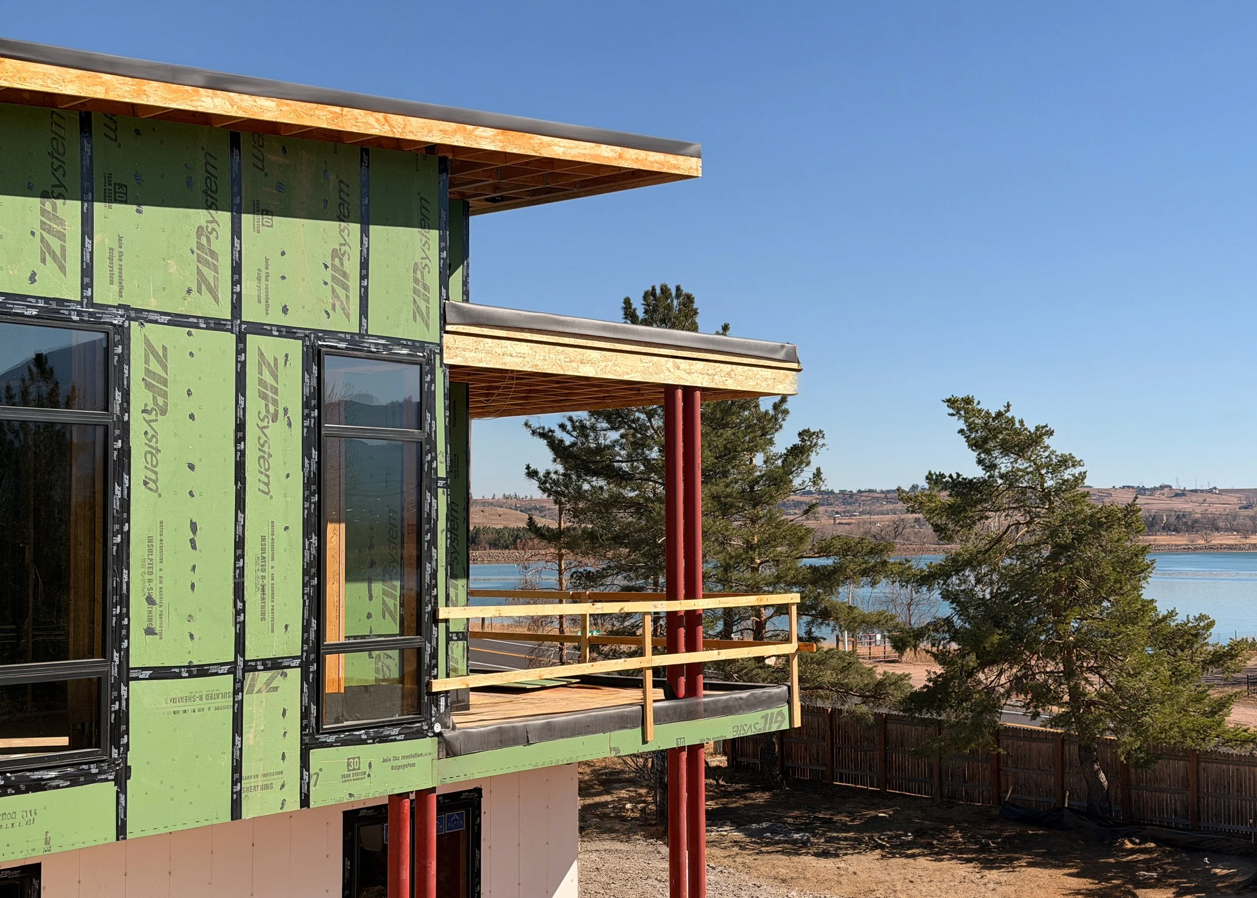 Modern residential building under construction with Sopher Sparn Architects overseeing construction phase services, featuring exposed structural elements and Boulder Reservoir views in the background.